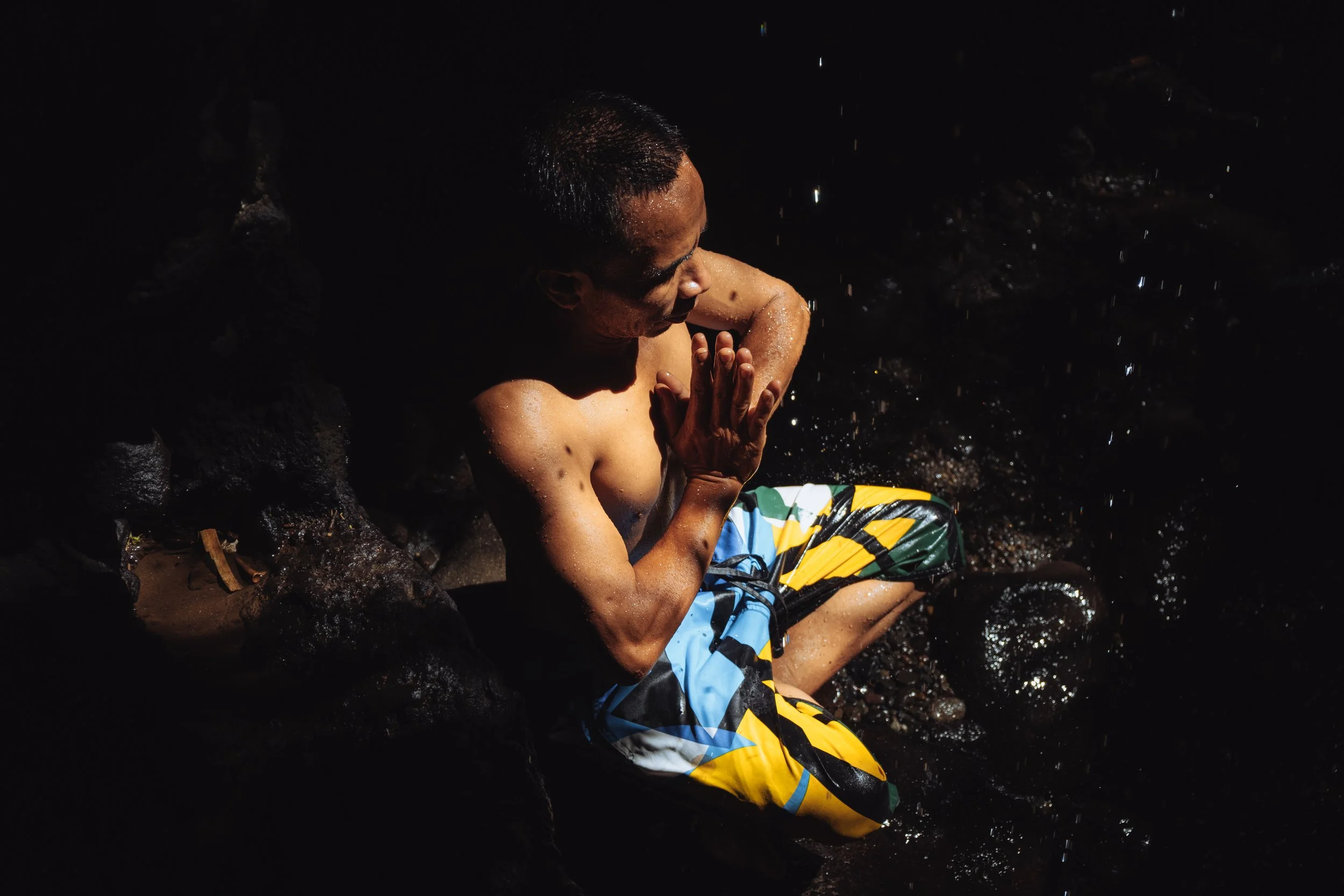 Un homme assis dans une rive rocheuse, en méditation, les mains jointes, au crépuscule ou à l'aube, avec une lumière douce.