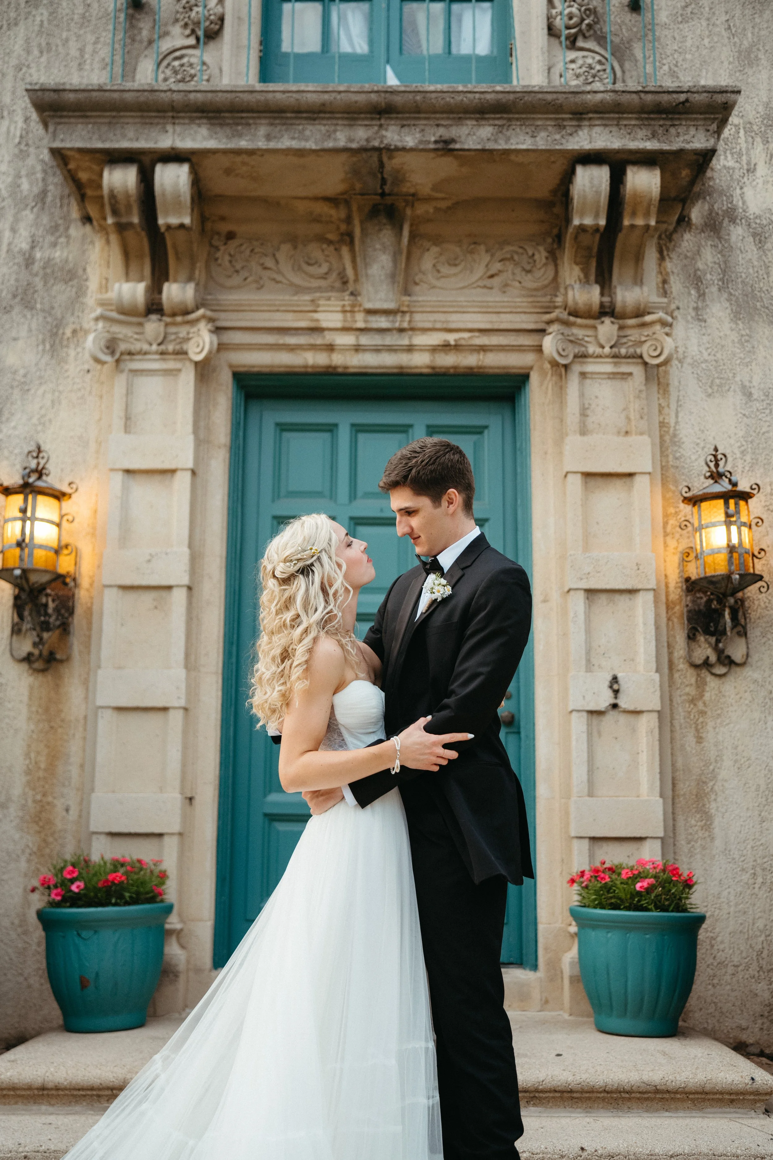 Bride and Groom embracing in front of teal doors of dresser mansion in Tulsa OK 