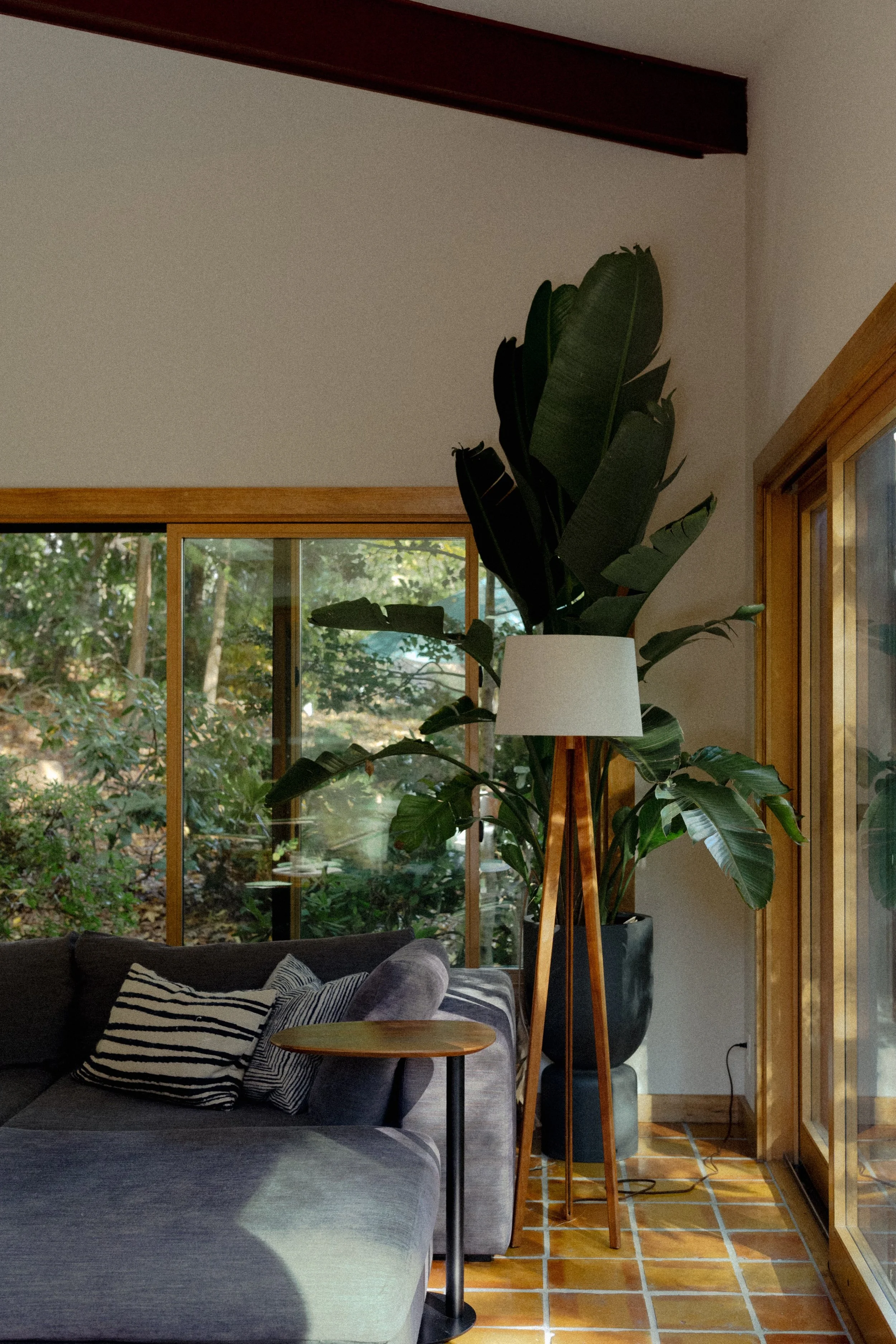 A photo of the inside of a midcentury modern sunroom with tiled clay floor and large sliding glass windows and doors.