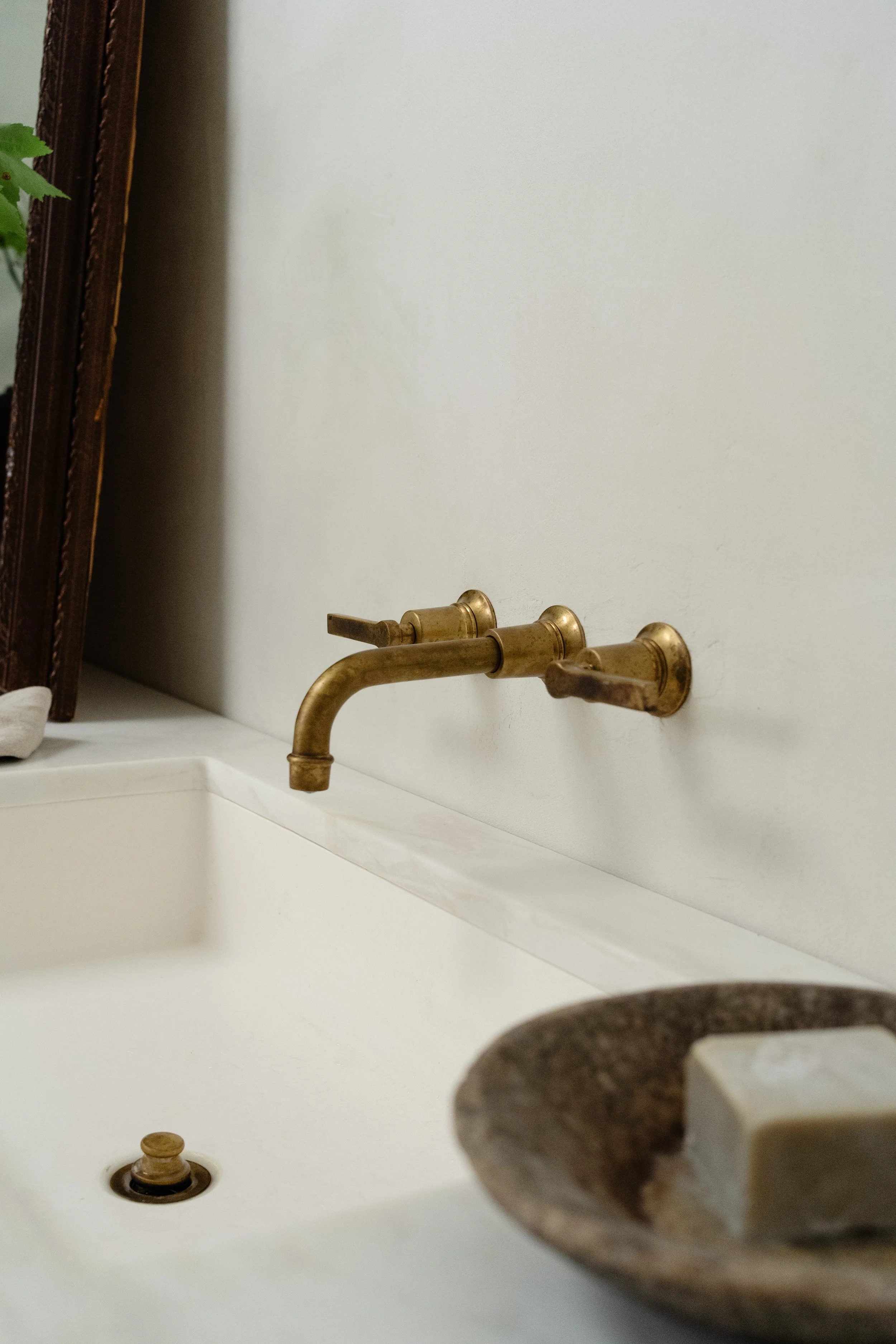 A countertop view of the master bathroom sink and brass fixture that sits over the bathroom.