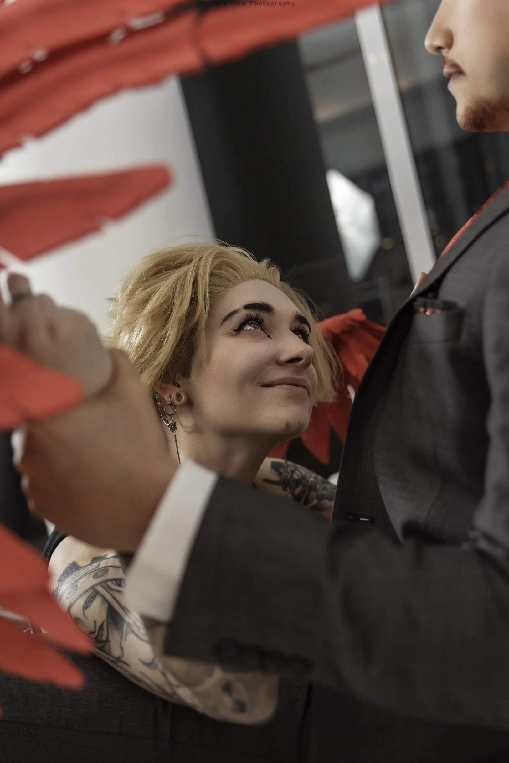 Hawks on his knees, smirking up at Endeavor, who holds Hawks' wrists in his hands.