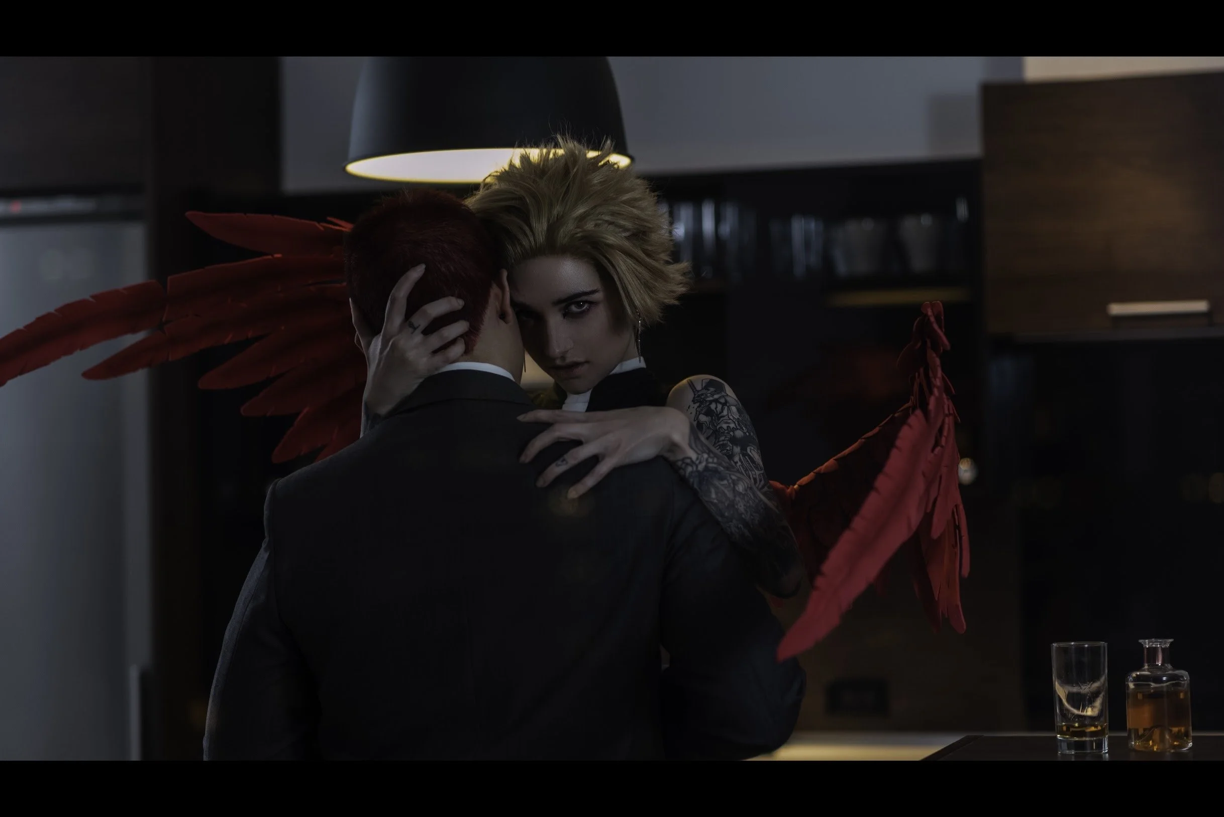 View from a distance; the condo is darkened. Hawks sits on a counter, Endeavor pressed up between his legs.