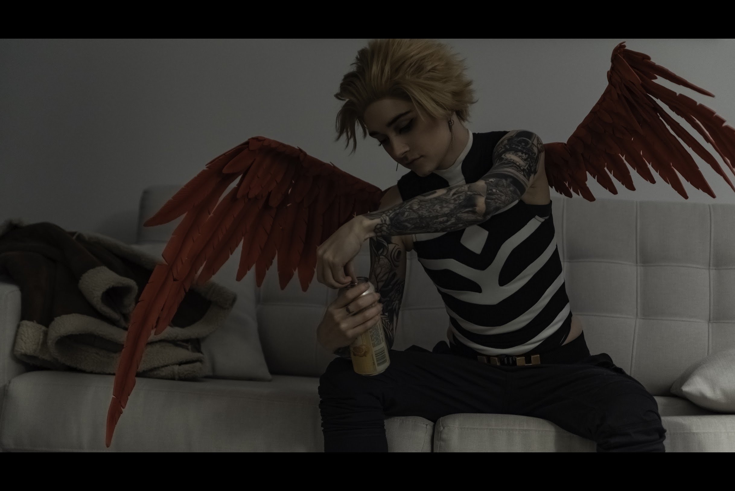 Now seated on the couch, Hawks opens one of the cans from the six pack.