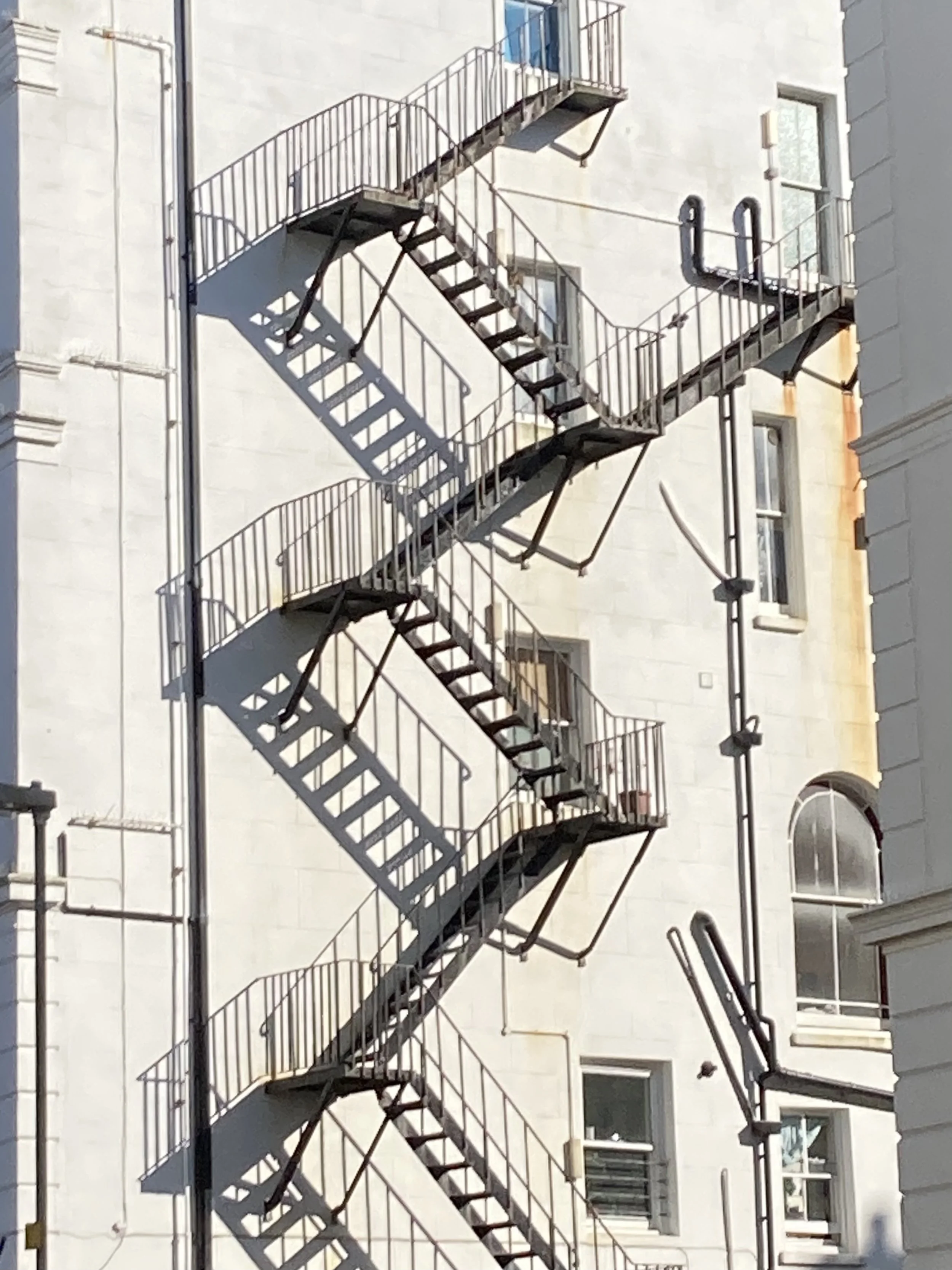 Fire escape staircase representing the journey of therapeutic coaching — layer by layer