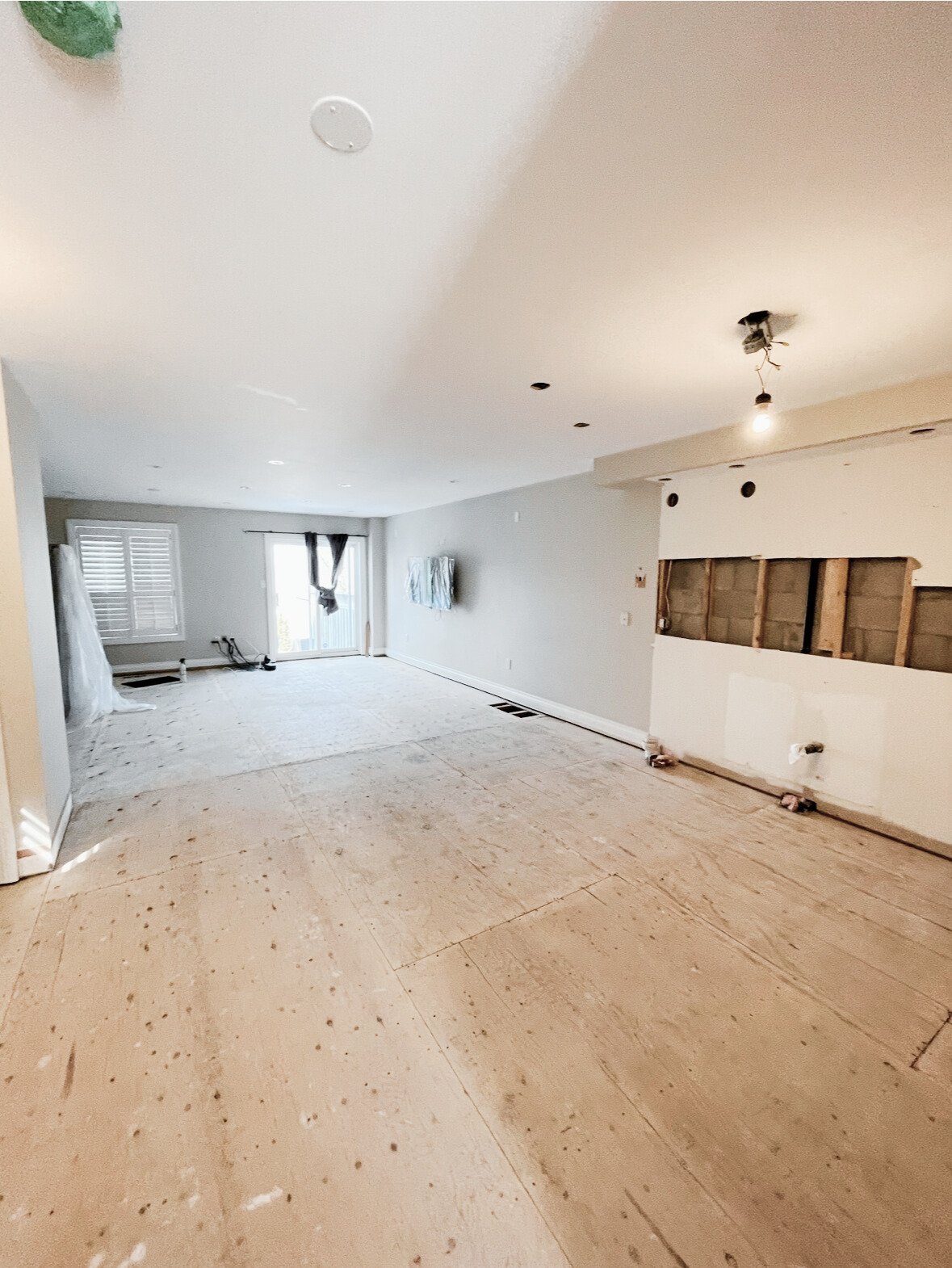 Room undergoing renovation with stripped floors and exposed walls.