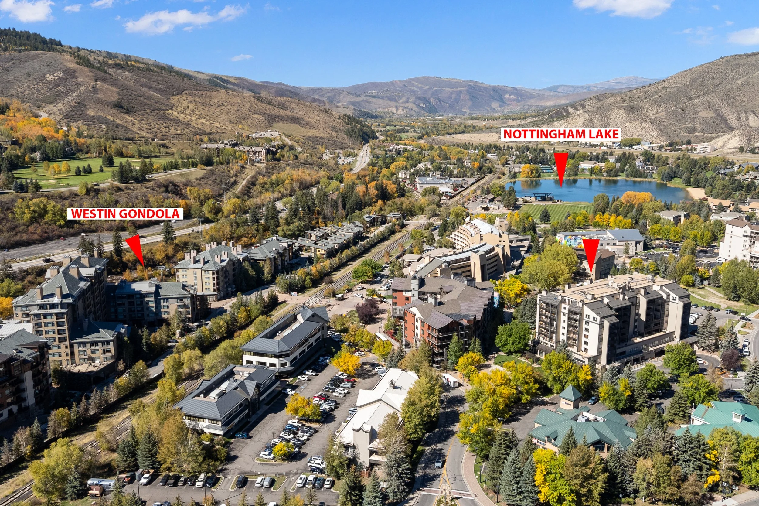 Aerial view of a mountain town with labeled Nottingham Lake and Westin Gondola surrounded by trees and buildings, with mountains in the background.