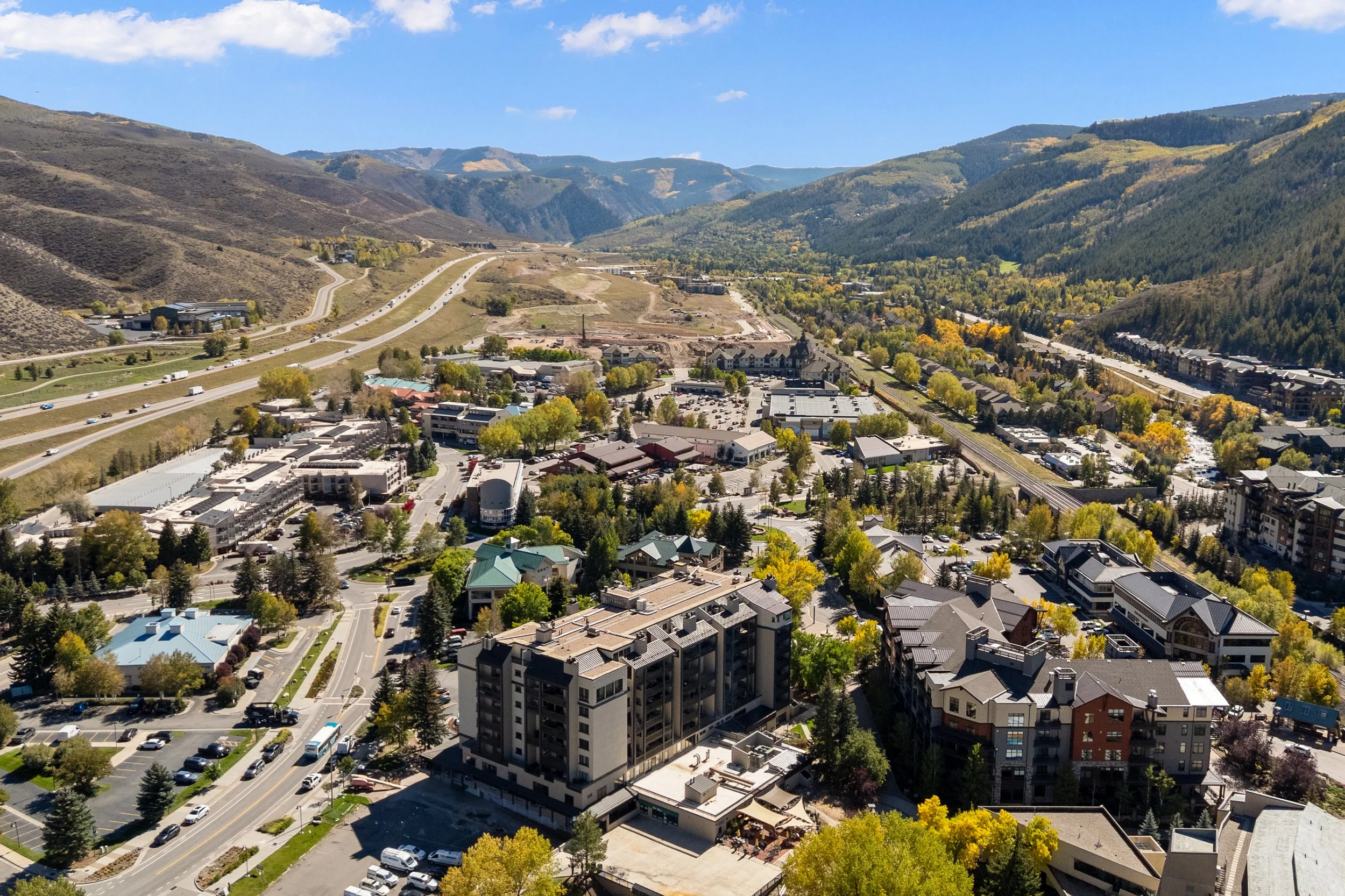 Aerial view of a small city in a valley surrounded by mountains with trees and clear skies.