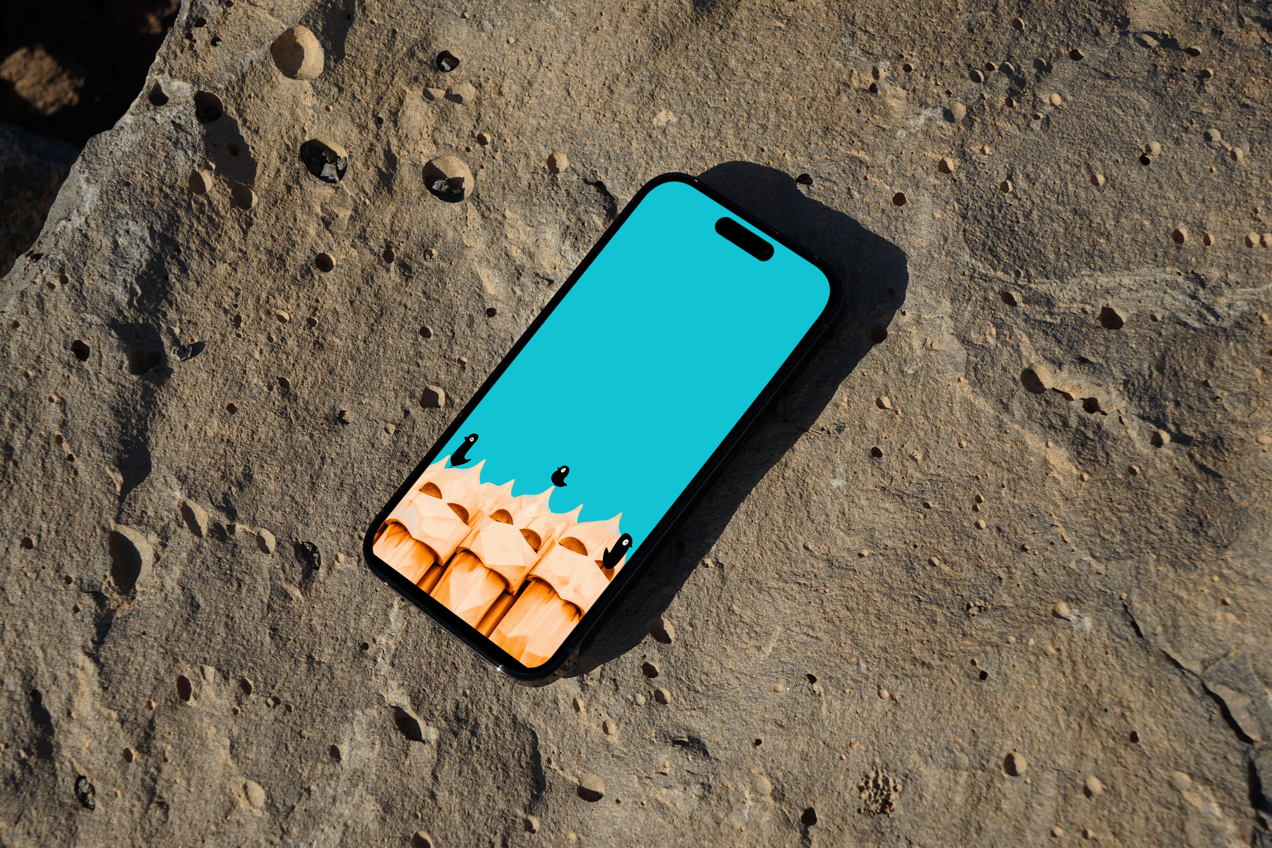 Teléfono móvil en una superficie de piedra con pantalla azul y caricaturas de palos de cabello y pequeños animales en la pantalla.