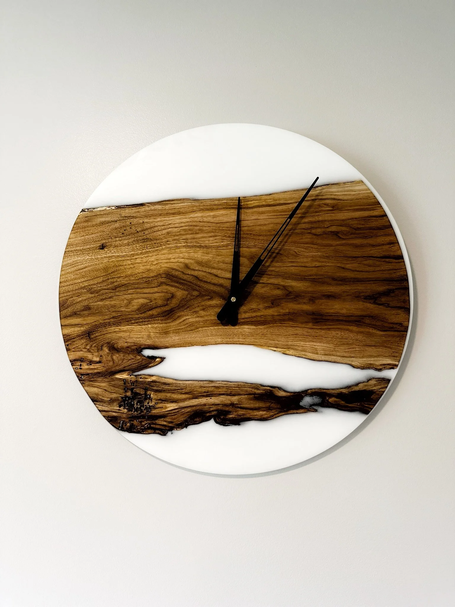 Modern wall clock with a design of wood and white resin, featuring black hands.