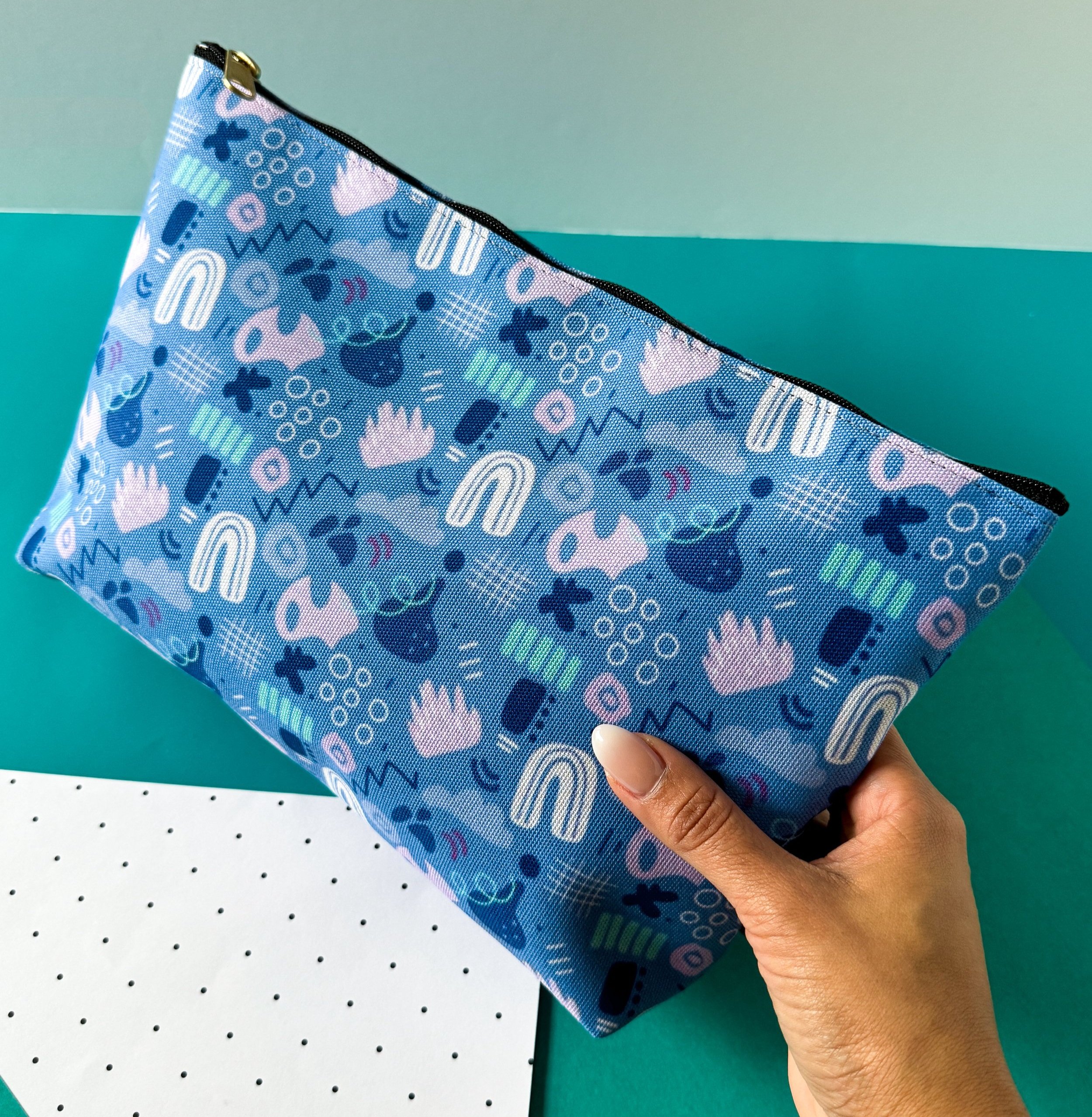 abstract shapes and lines pattern in a fabric pouch perfect for gifting, traveling and as a pencil case in blues, teals and light purples