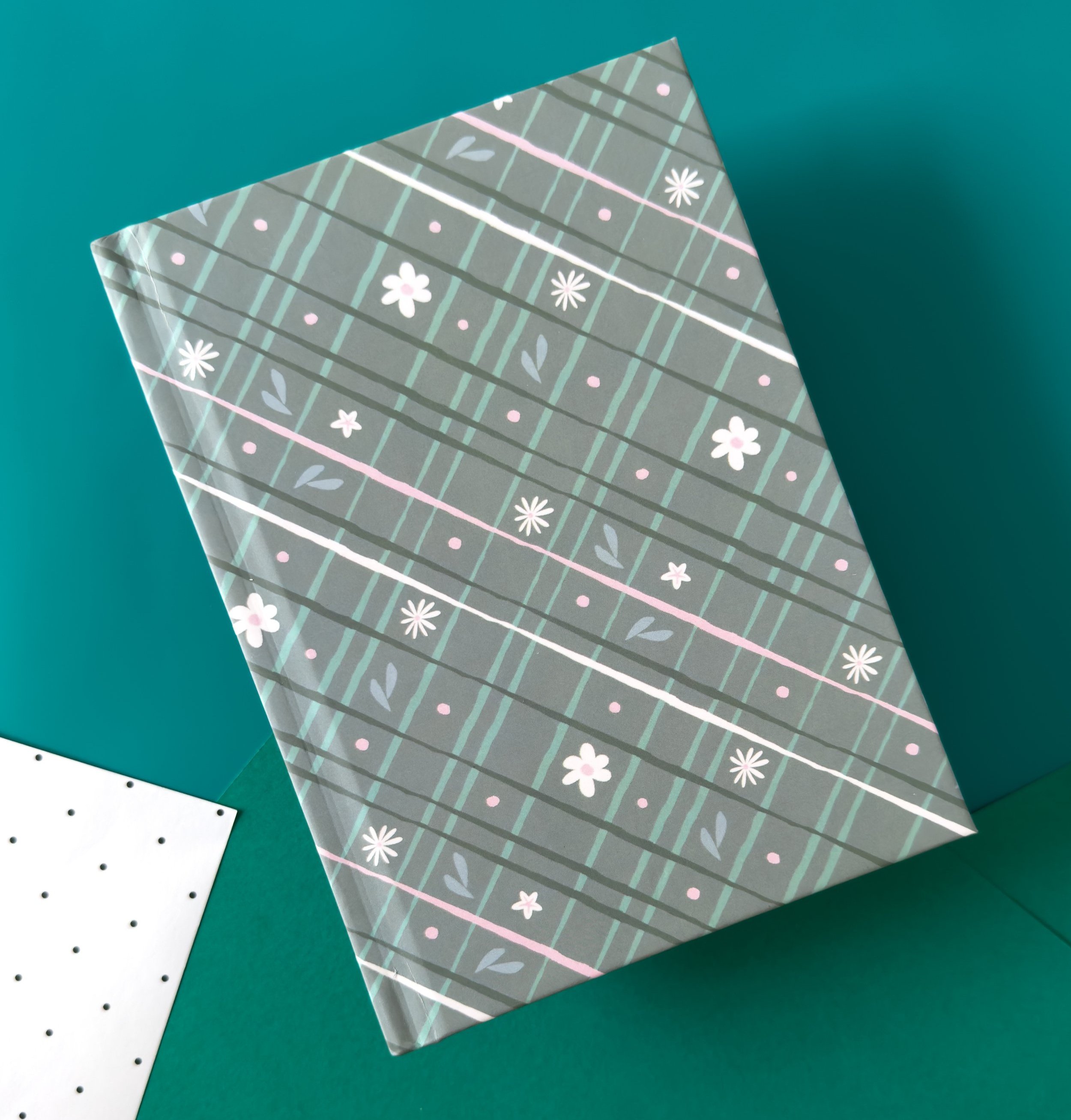 notebook with hardcover and a cozy plaid pattern hand drawn and illustrated in greens, creams, light pinks and teal