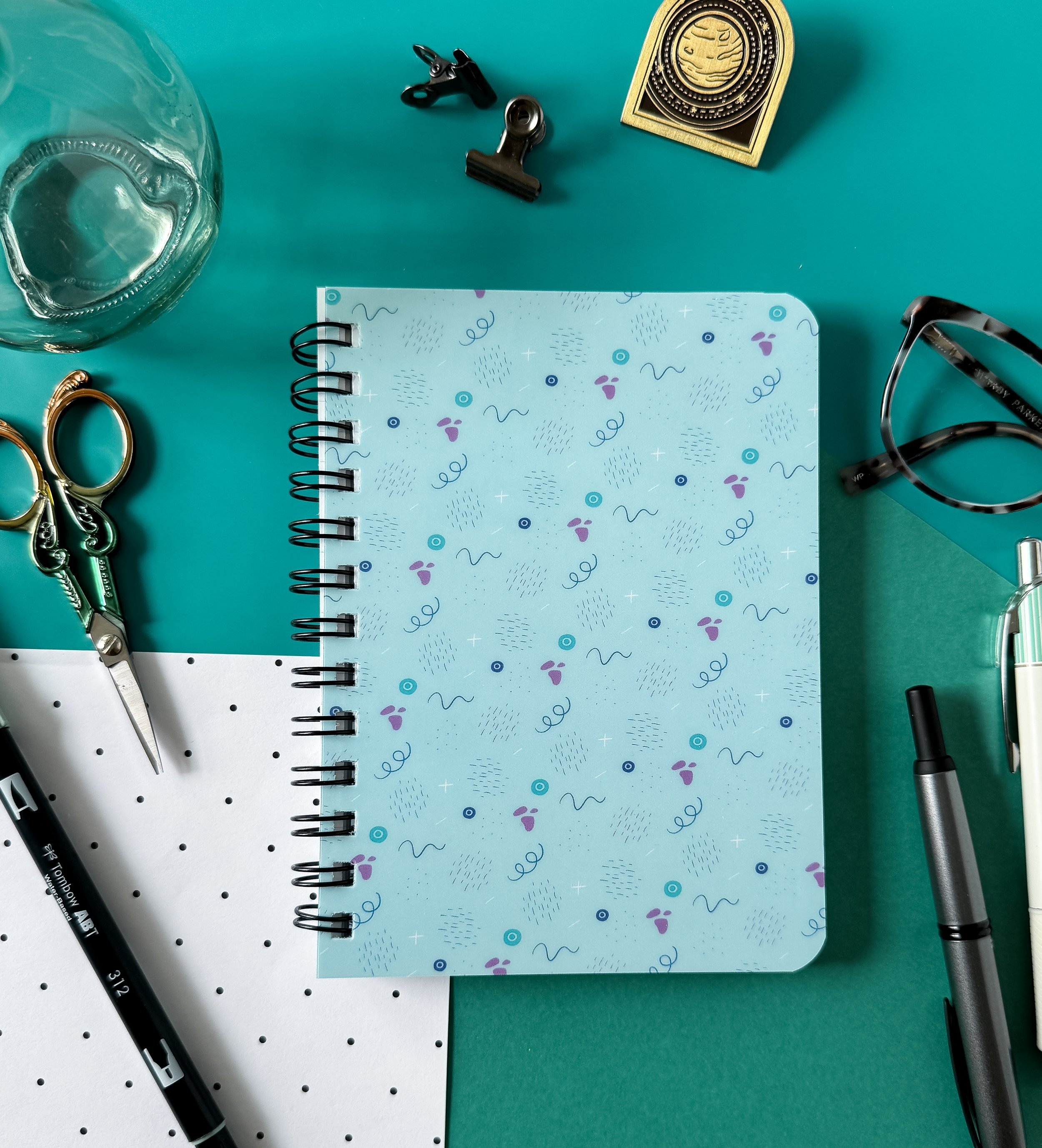office supplies with spiral bound notebook with a pattern of lines and abstract shapes