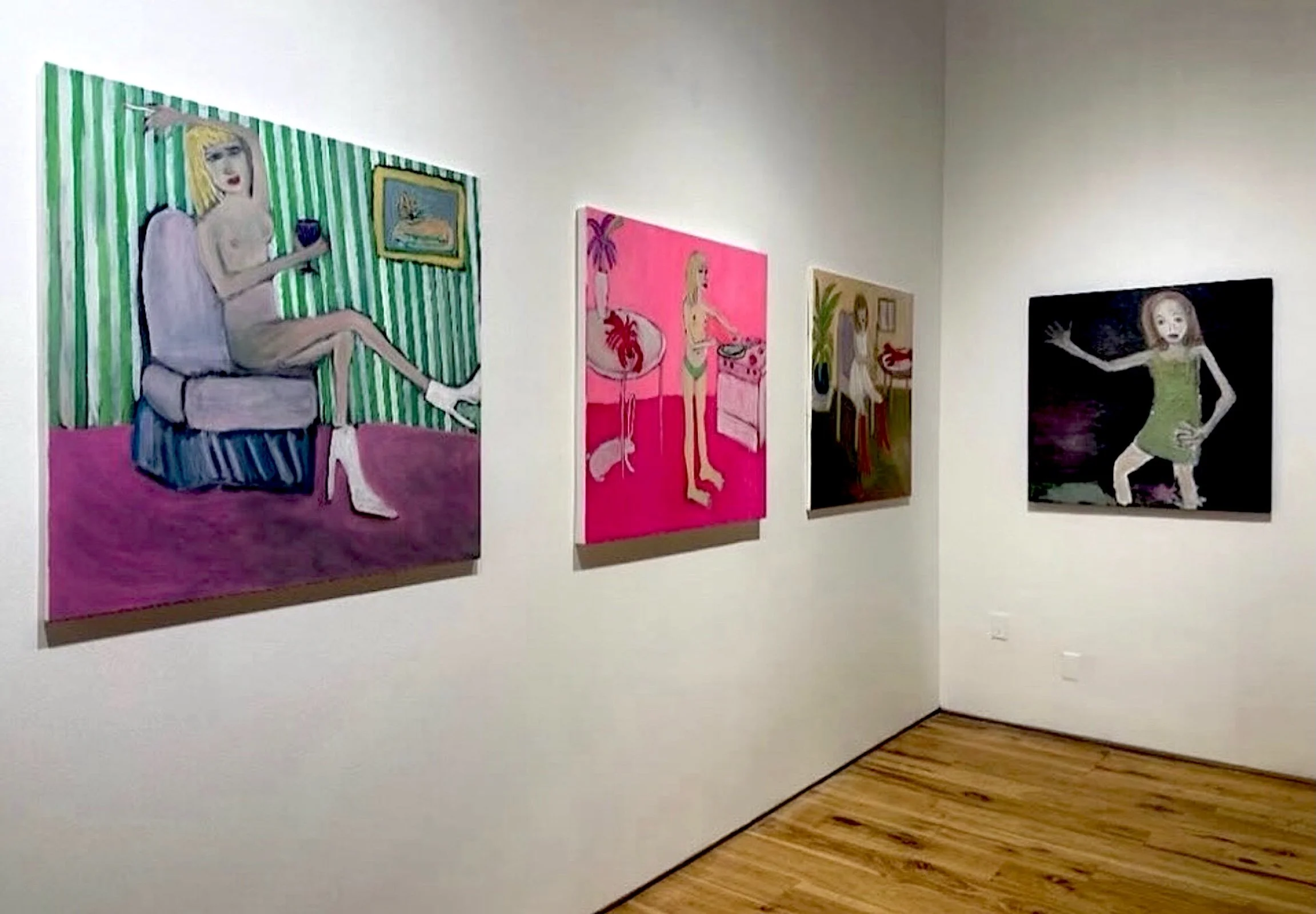 Gallery wall with four paintings featuring women, set in an art gallery with a wooden floor and white walls.