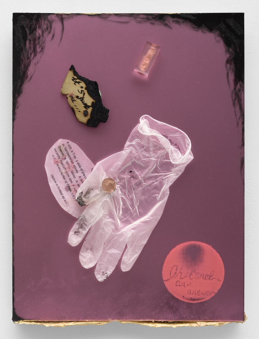 Collection of objects on a pink surface, including a black and yellow fabric tag, a small plastic container with a pink substance, a clear plastic gloves with a small black spot, a pink cigarette pack, and a red object with blacked-out areas and handwritten text.