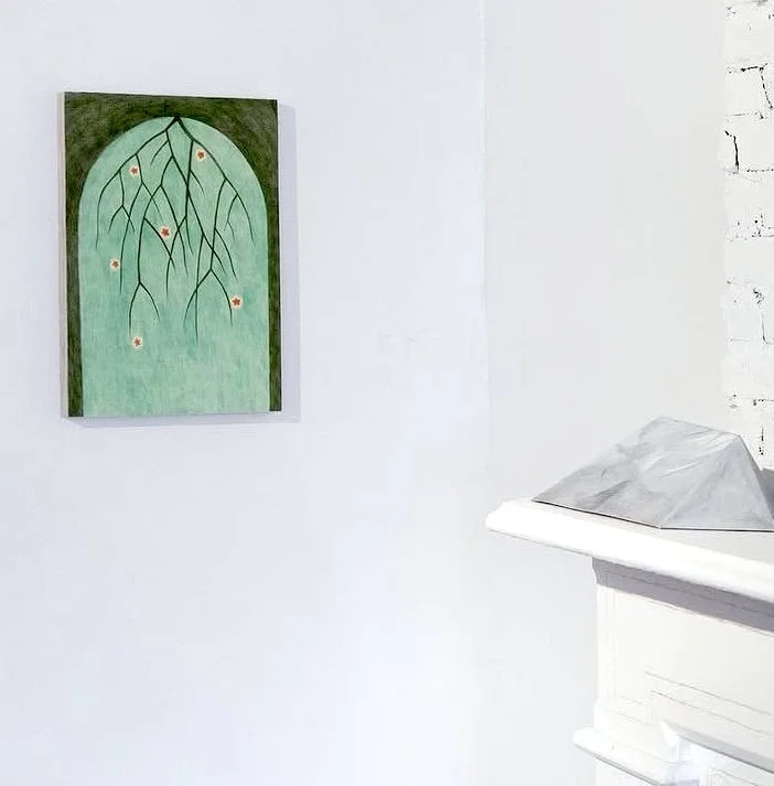 A painting of tree branches with small red flowers hanging on a green background, mounted on a white wall.