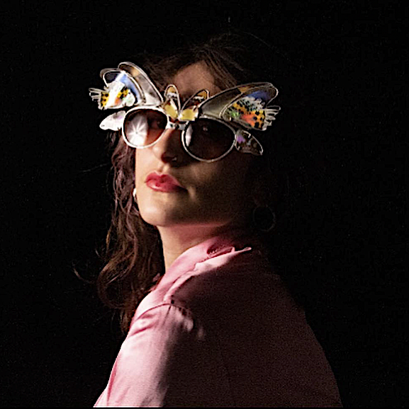 A woman wearing pink lipstick and sunglasses with decorative butterfly and flower embellishments on the frames.