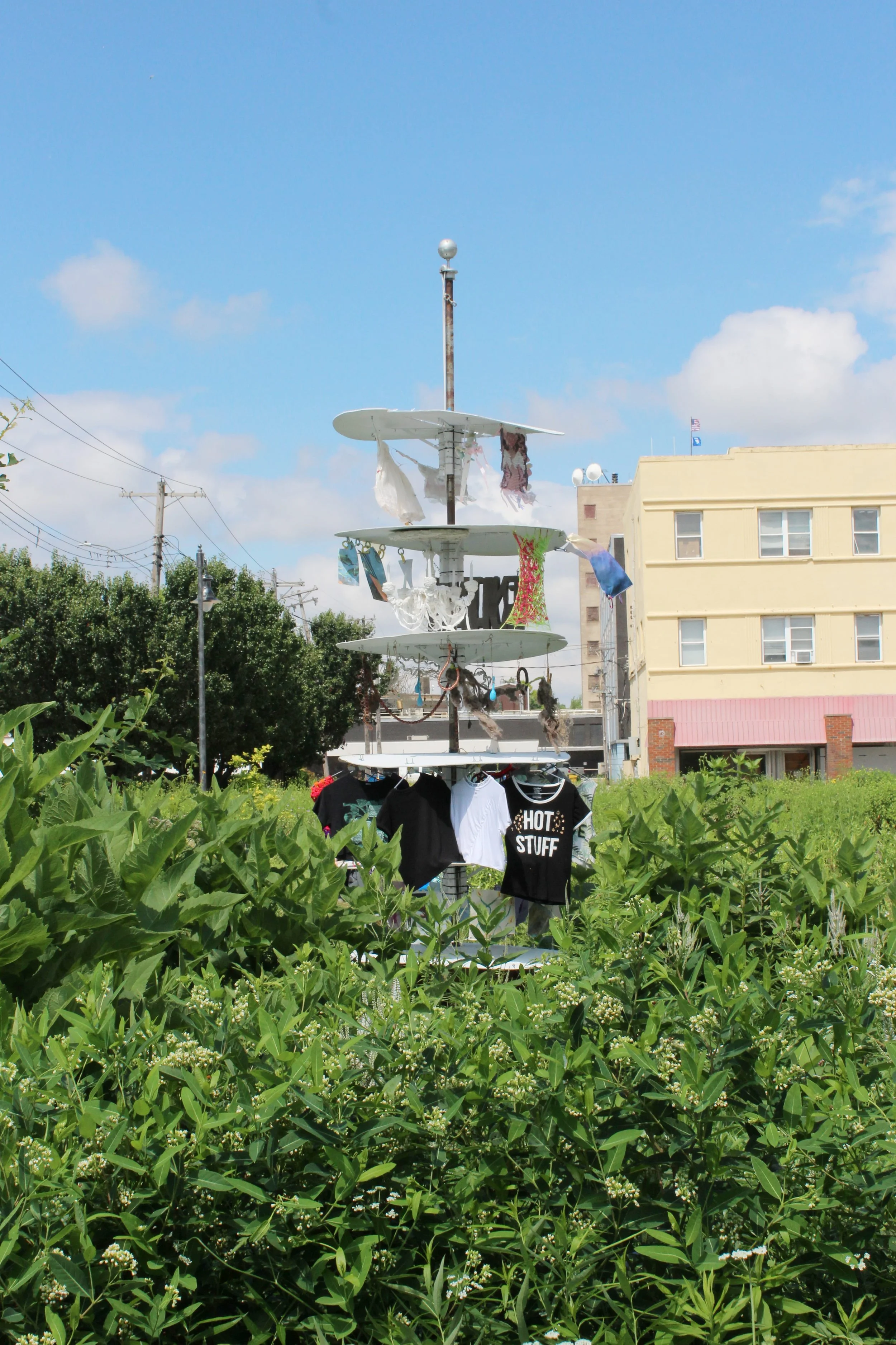 STNDRD flagpole collaboration between the waiting room and purple window gallery photographed in front of hedges and a residential complex