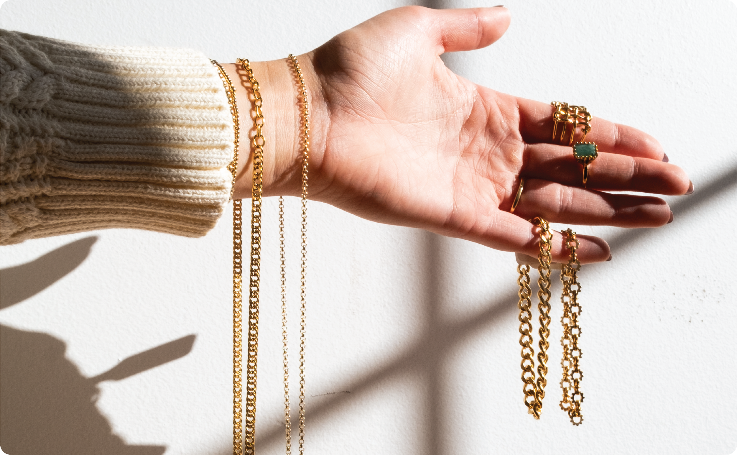 Lifestyle product photography featuring layered gold necklaces and rings.