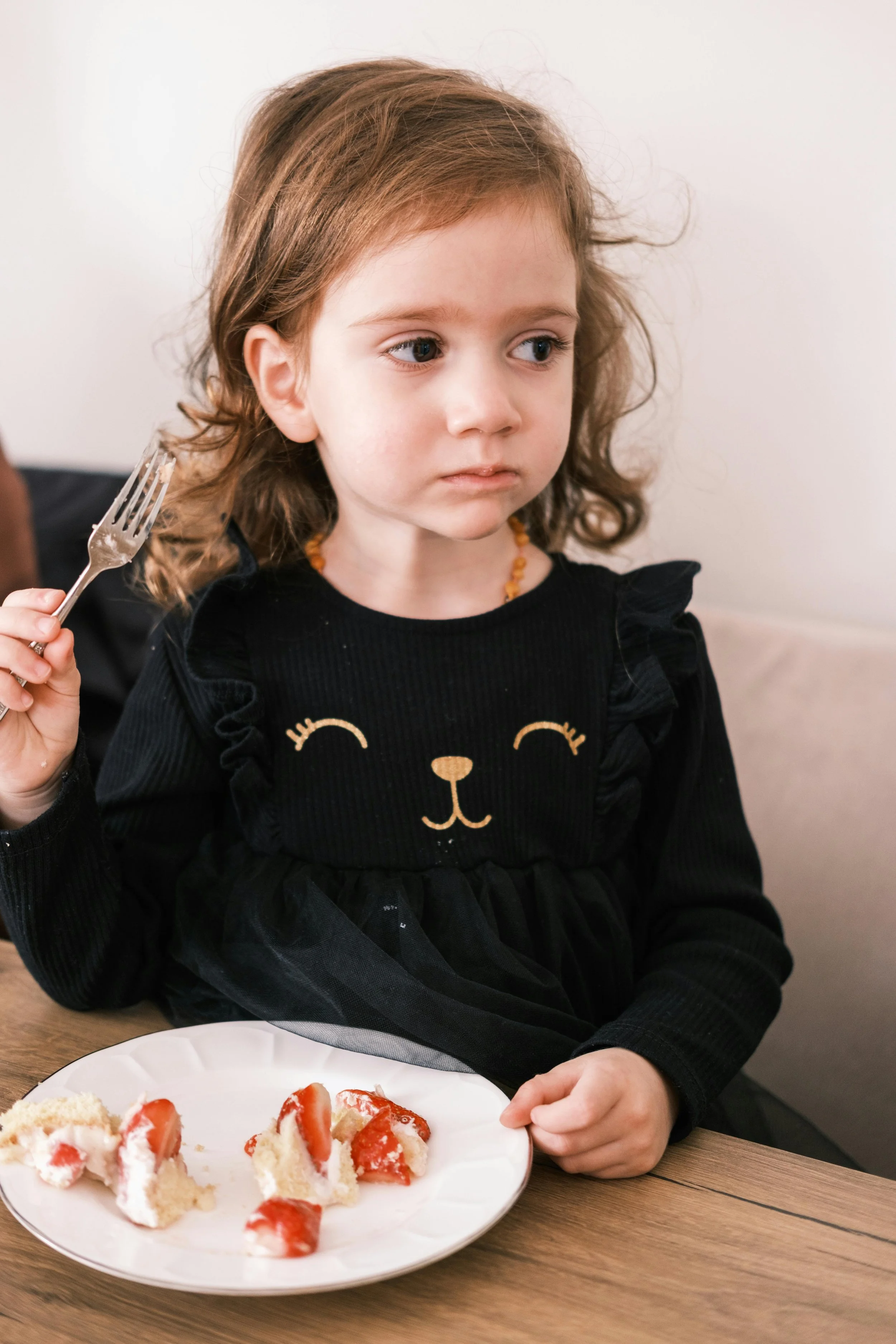 A girl trying to eat cake with a fork
