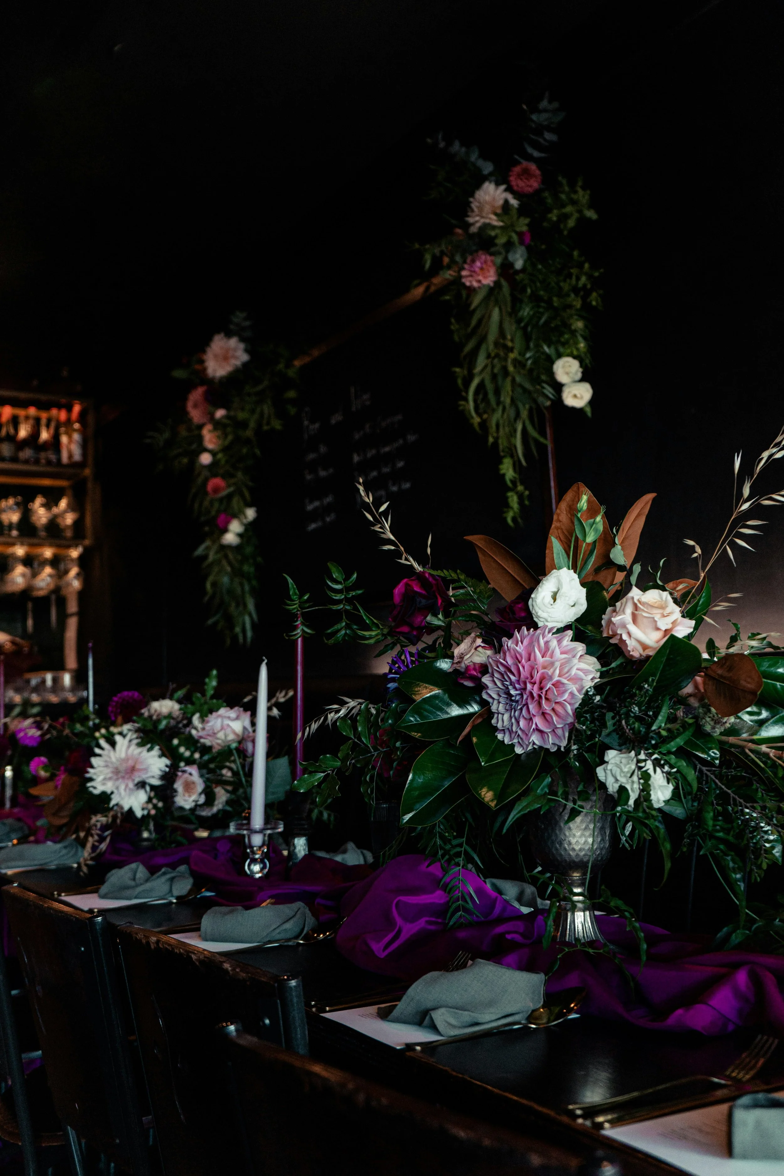 Elegant dining table setting with floral centerpieces and dark decor.