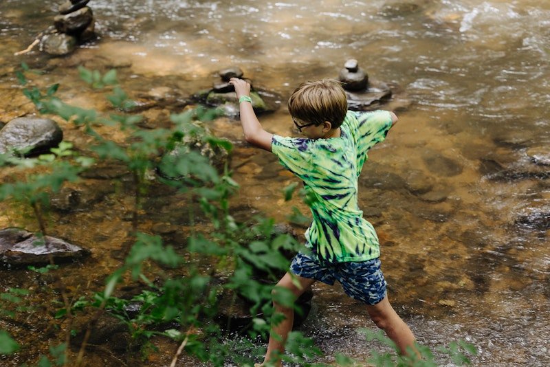 Boy playing in the creek at Christian summer camp 