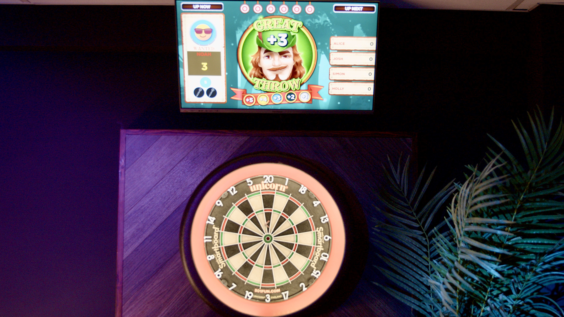 Digital dartboard setup with a score display above, showing a character and scores for players.