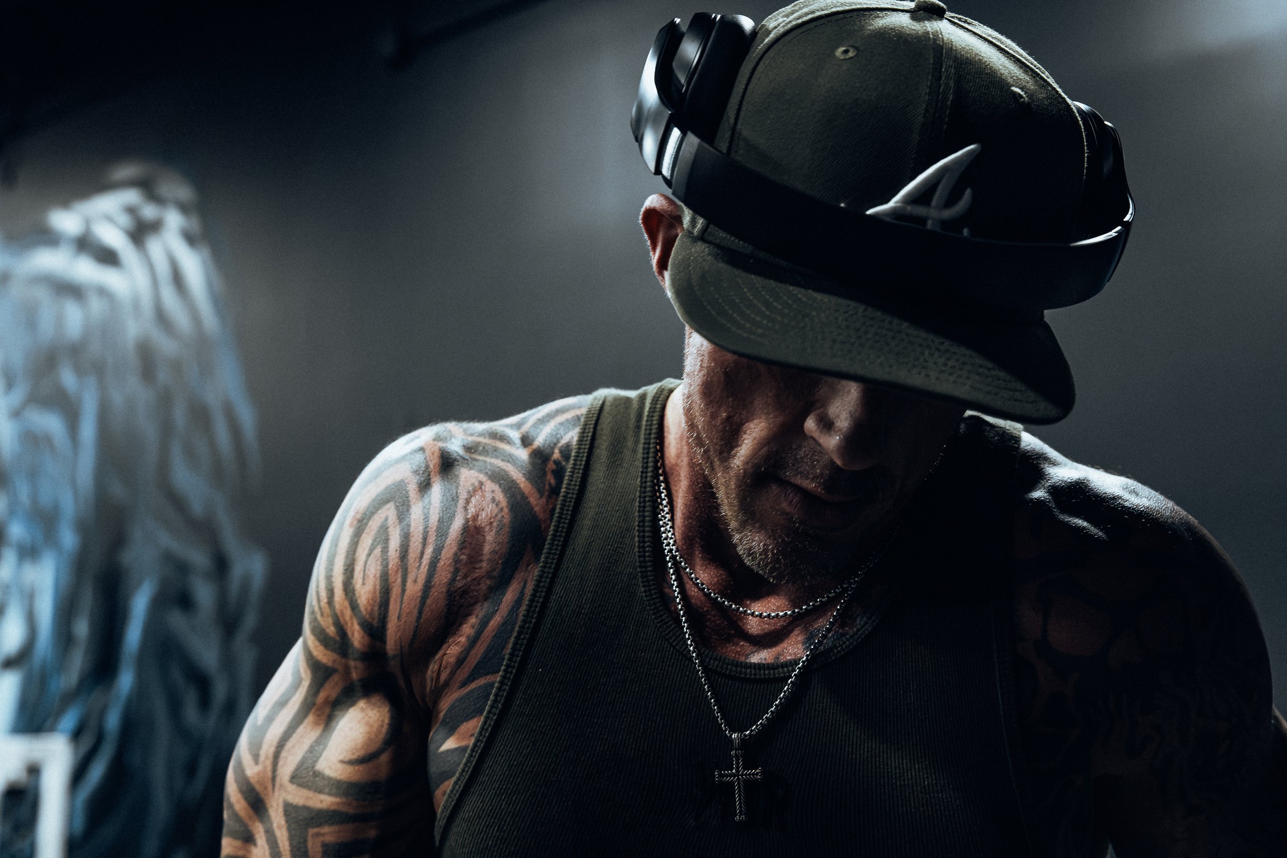 Moody gym portrait, cap and headphones, looking down.