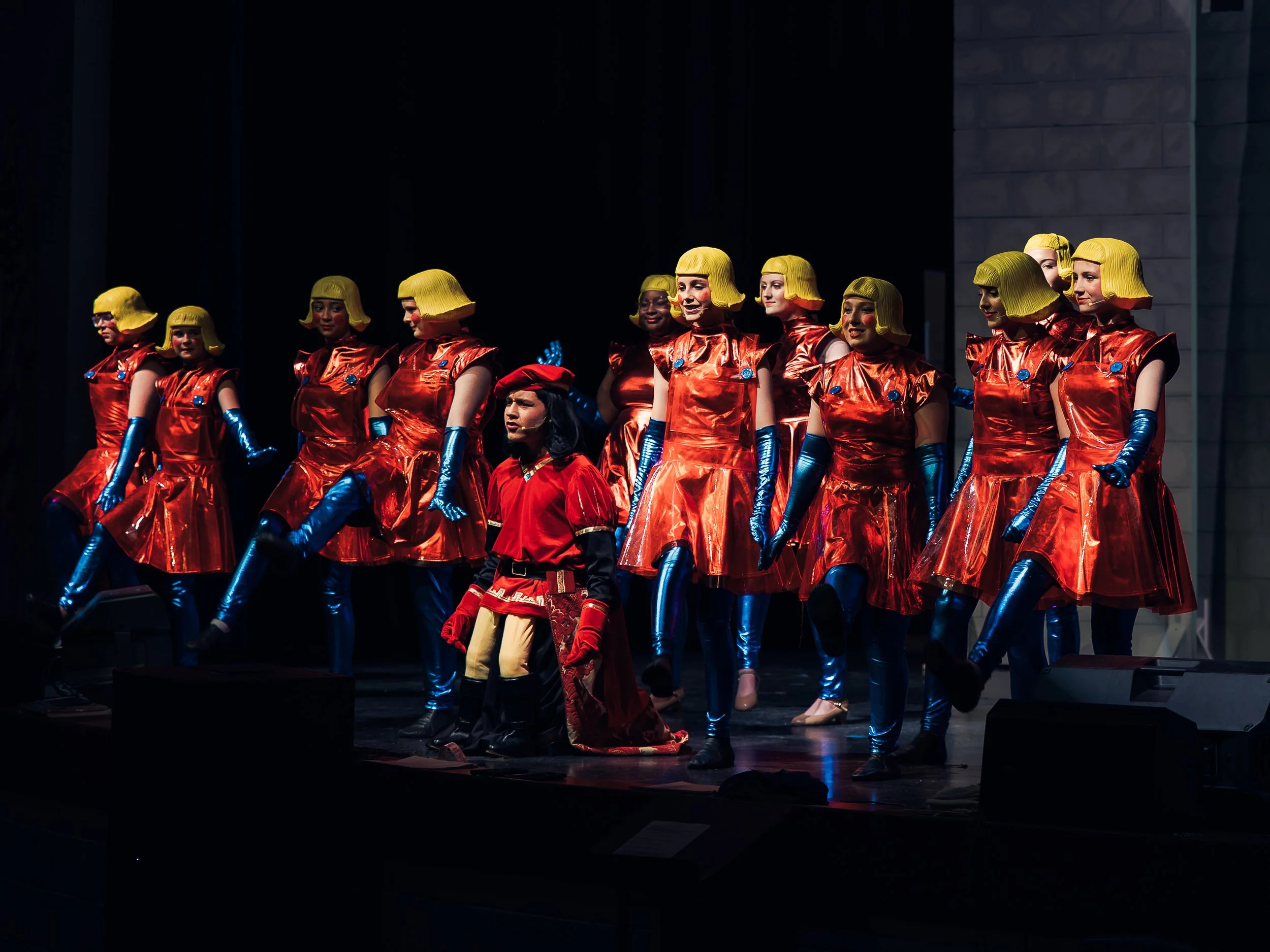 Lord Farquaad and the Duloc chorus in red, blue, and yellow on stage.