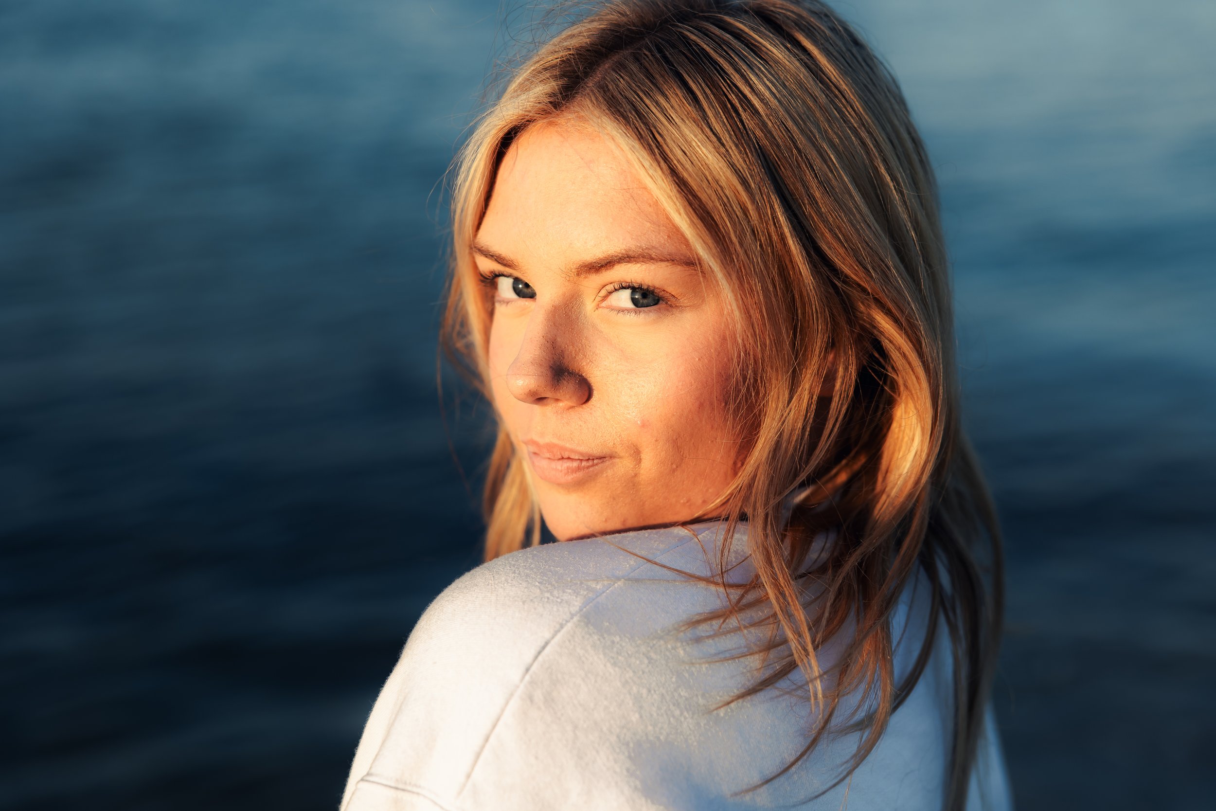 Blonde woman looking back, water behind