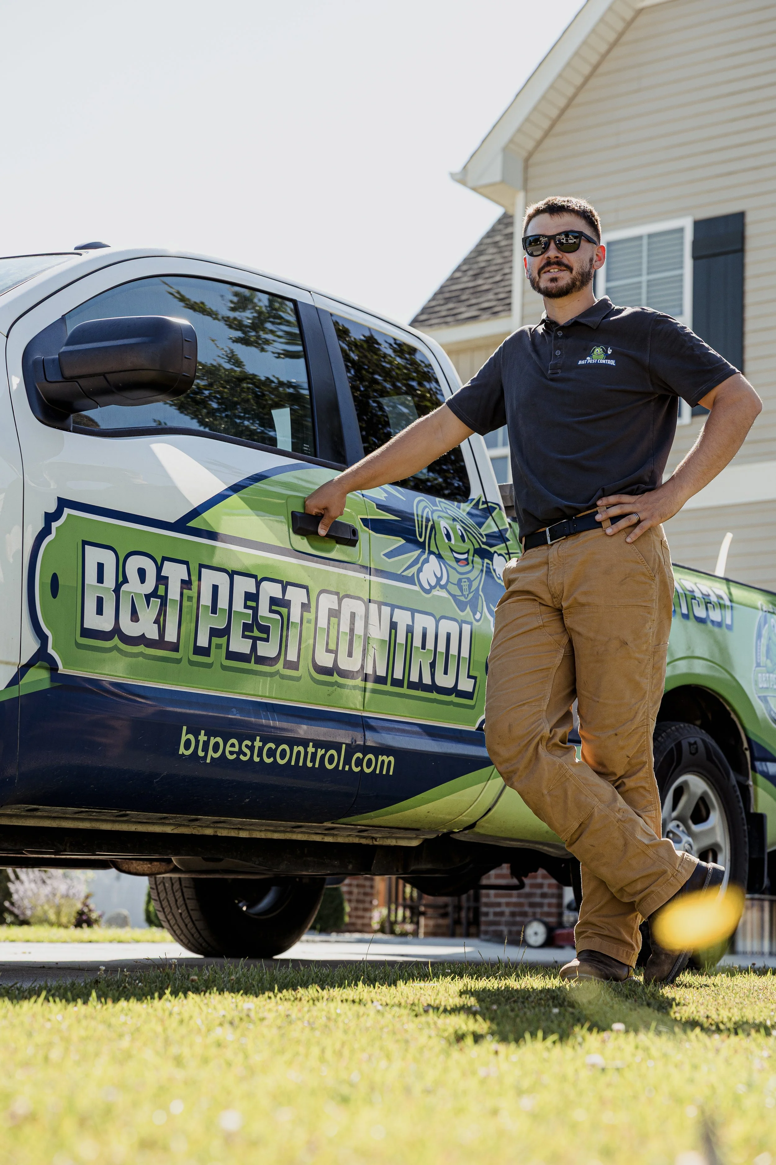 B&T Pest Control technician leaning on a branded white pickup.