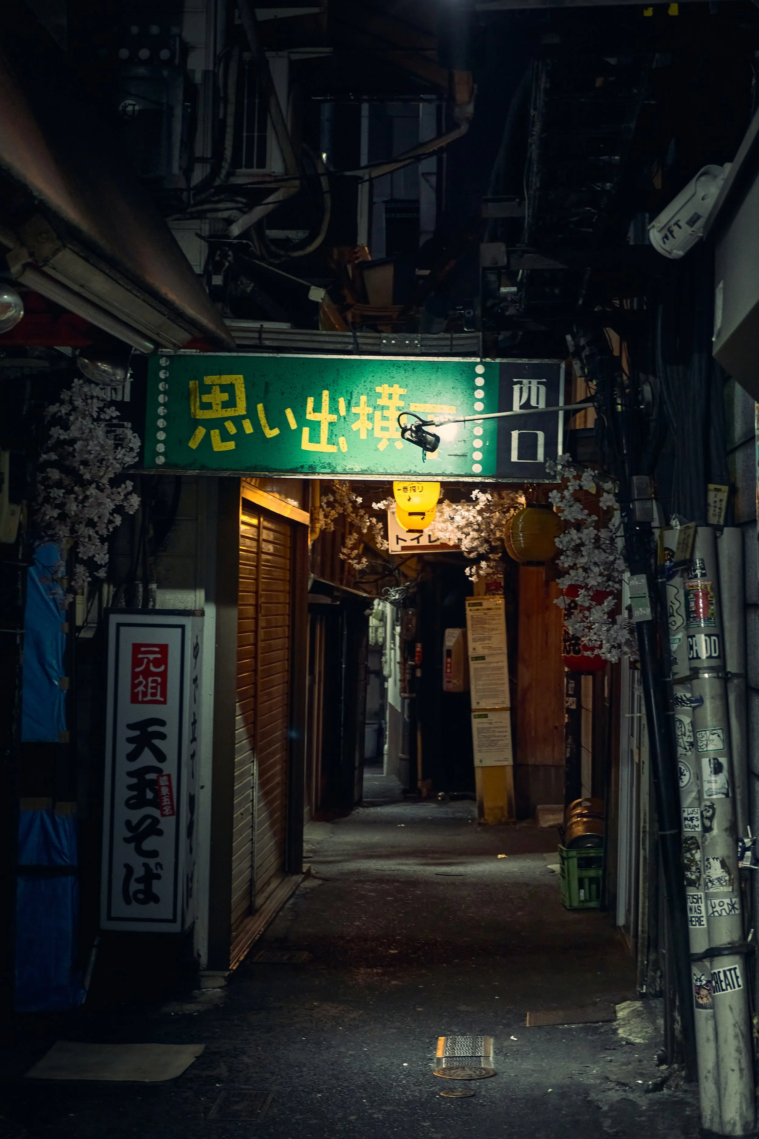 Narrow dimly lit alley with Japanese signs and lanterns in Tokyo.