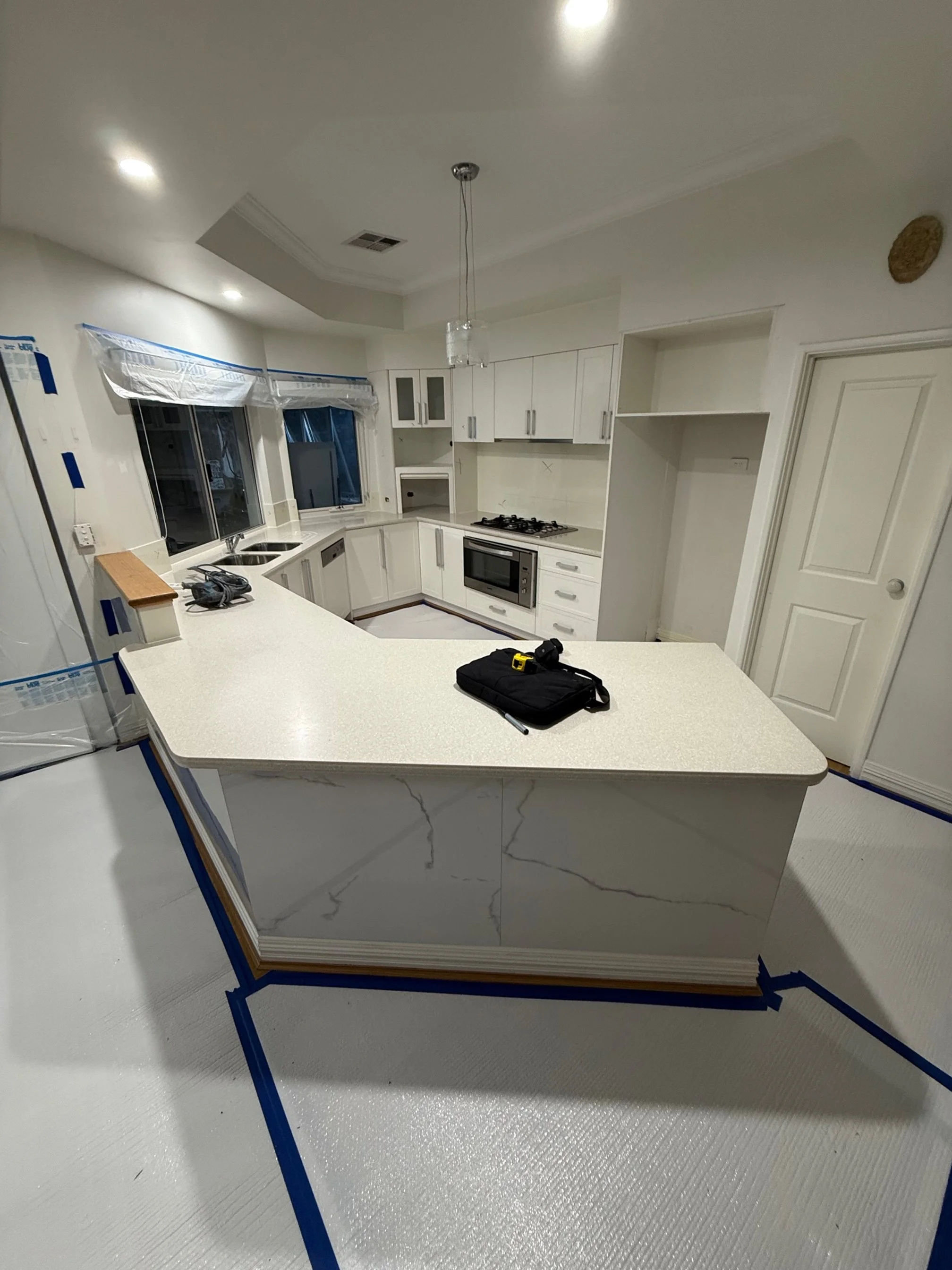 Kitchen with white cabinets, a central island, and stainless steel appliances, under construction or renovation.