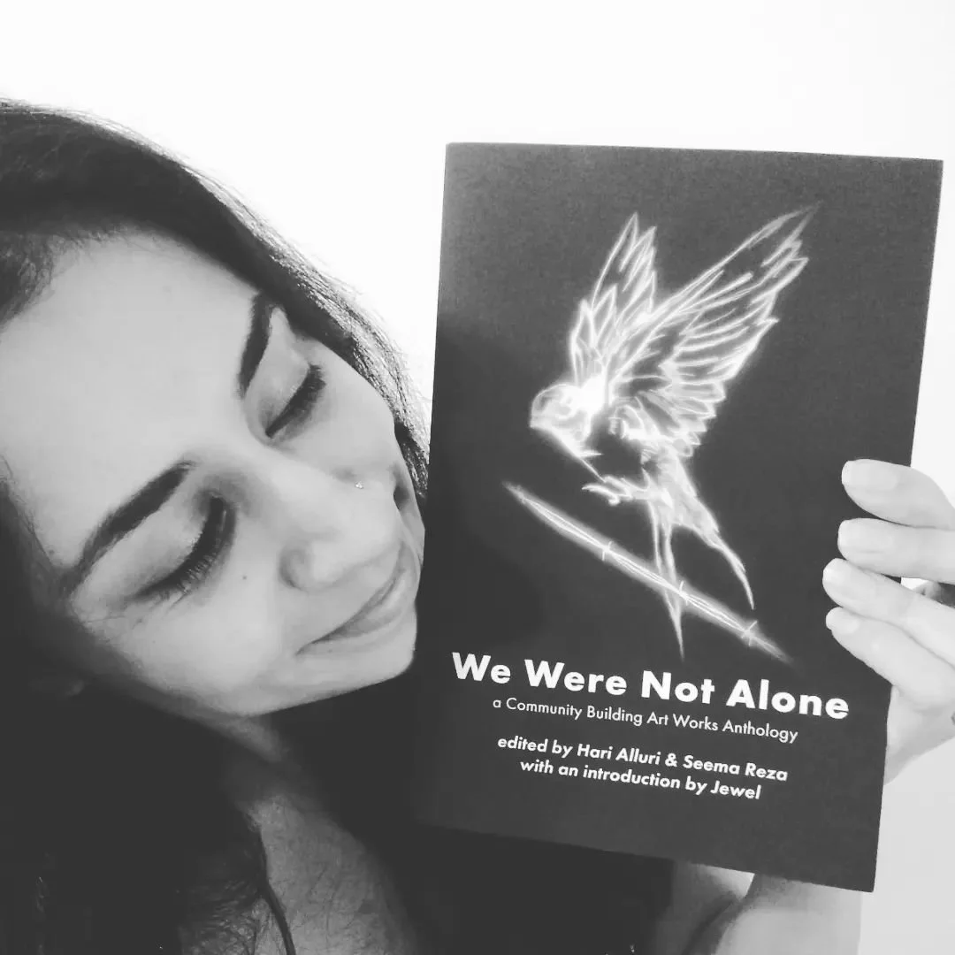 A woman with closed eyes smiling and holding a dark-colored book titled "We Were Not Alone" with an illustration of an angelic figure with wings.