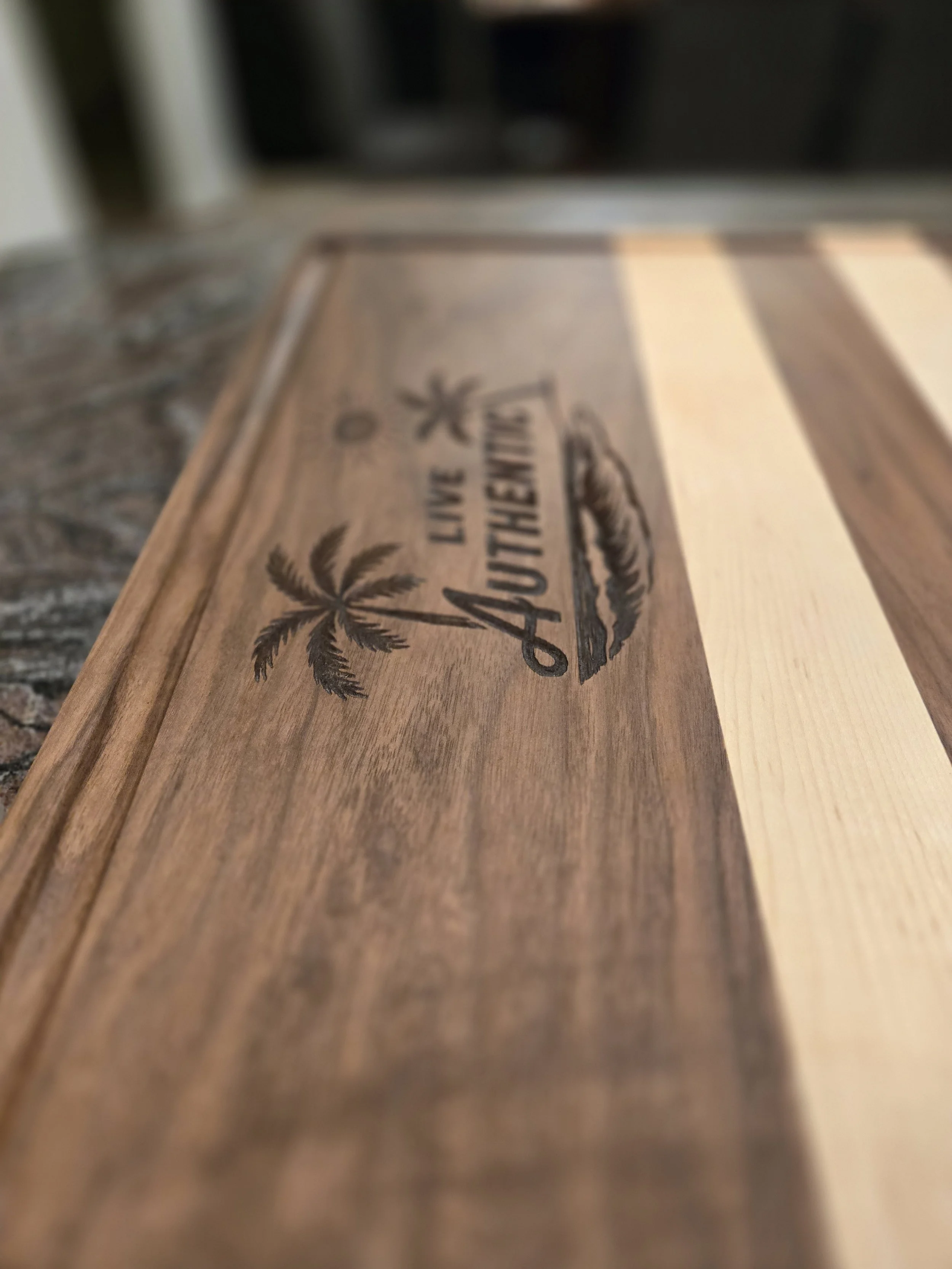 Cutting board made from walnut and maple with "Live Authentic" laser engraved in the walnut.