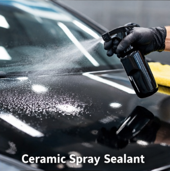 A person wearing black gloves spraying ceramic spray sealant onto a car's surface in a garage or workshop.