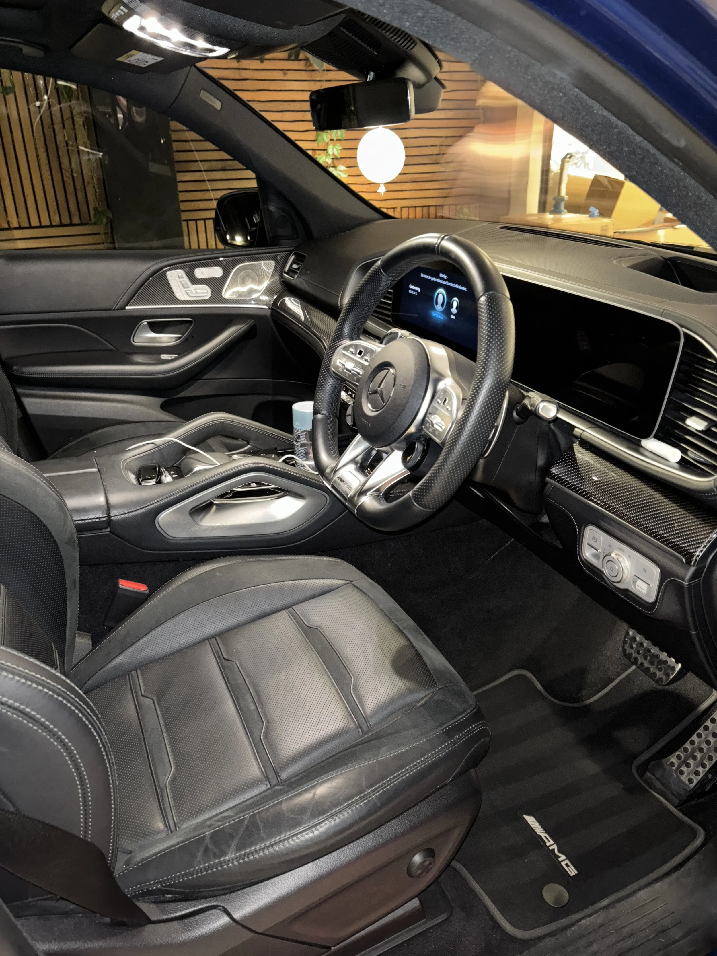 Interior of a luxury Mercedes-Benz AMG vehicle, showing black leather seats, digital dashboard, steering wheel, and center console with various controls.