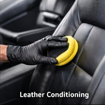 Person wearing black gloves using a yellow sponge to clean and condition a black leather car seat.