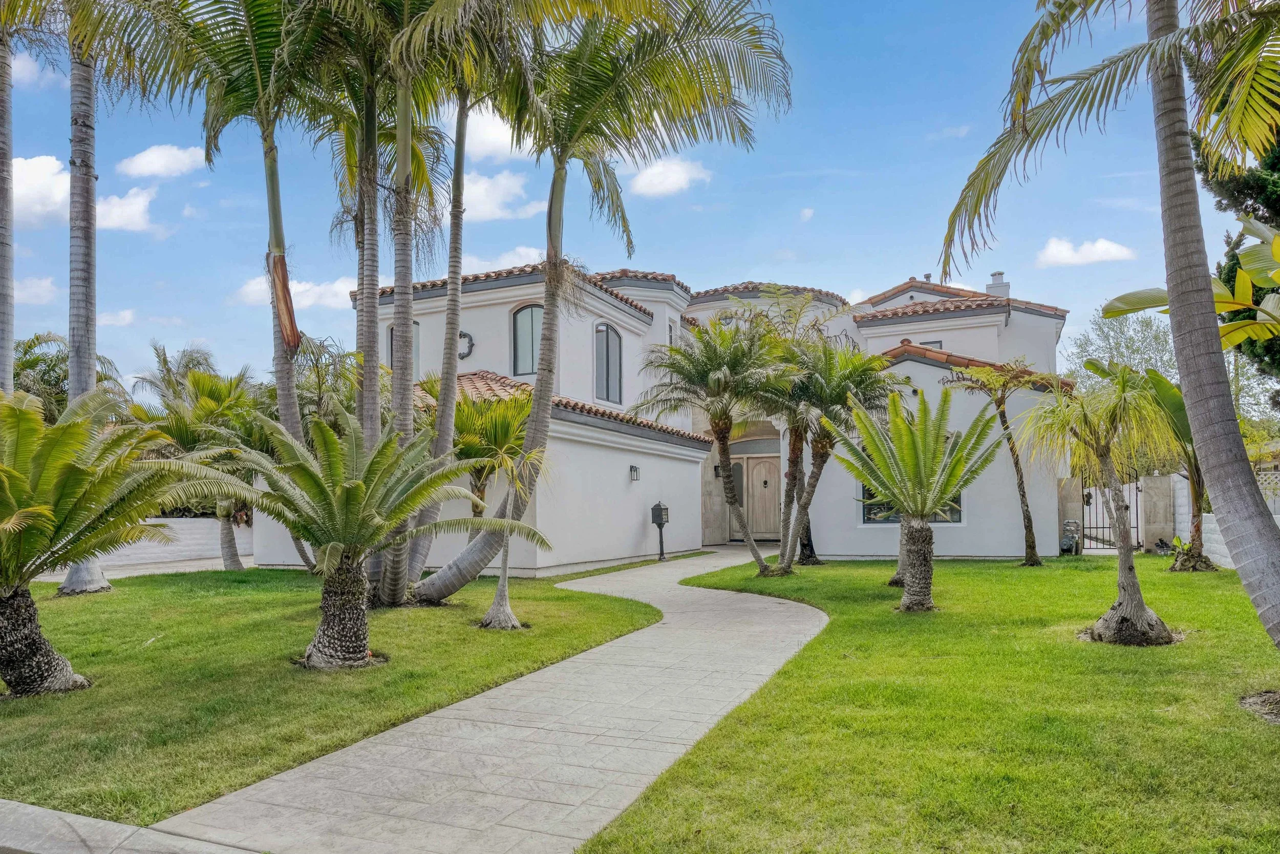 Exterior real estate photo of white home with palm trees and landscaped yard — San Diego property photographed by Magana Productions.
