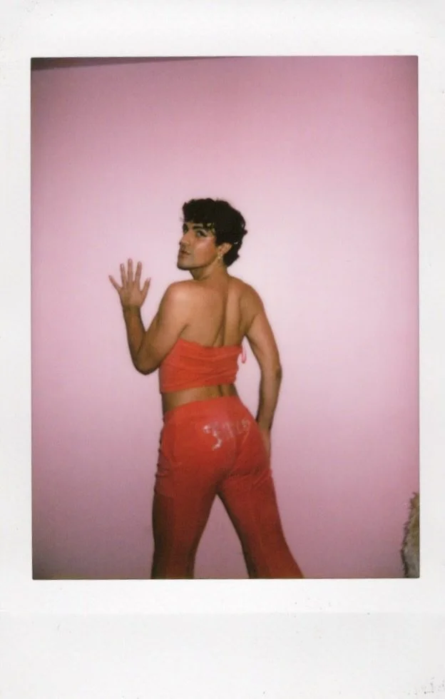 Person posing against a pink wall wearing a red outfit
