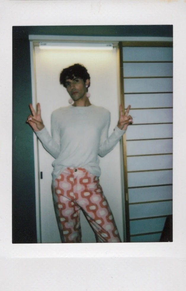 Person posing with peace signs, wearing a light-colored shirt and patterned pants.