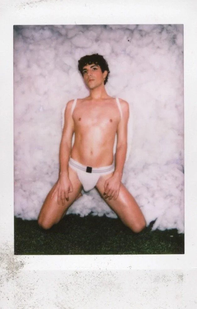 Person kneeling against a fluffy white background, wearing white underwear.