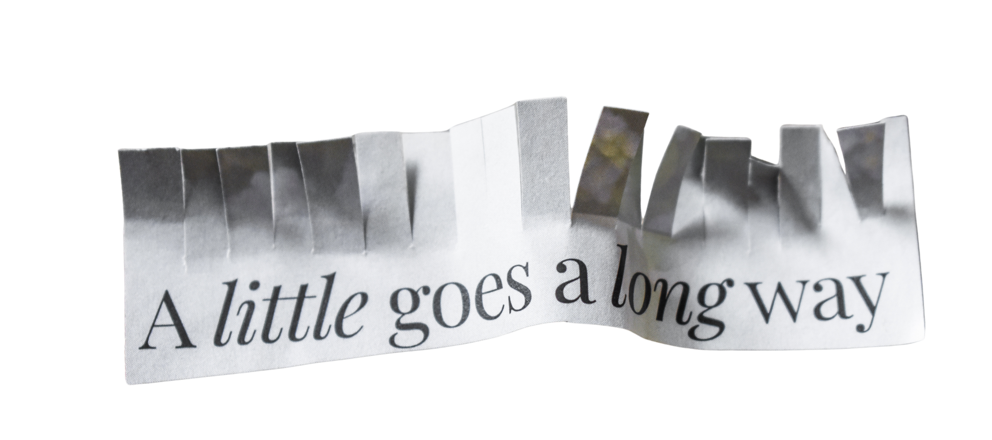 Paper strip with a fringed edge and the words 'a little goes a long way' printed in serif font