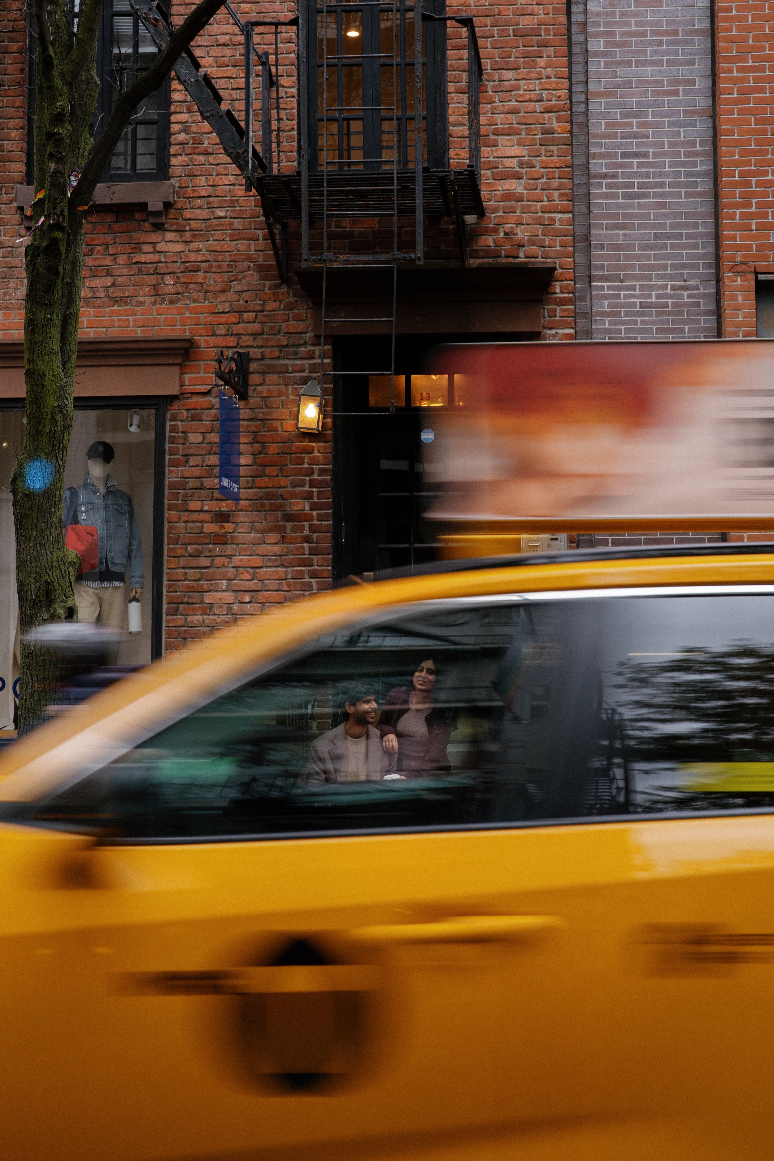 Couple hanging out on steps in the West Village while an NYC cab passes by