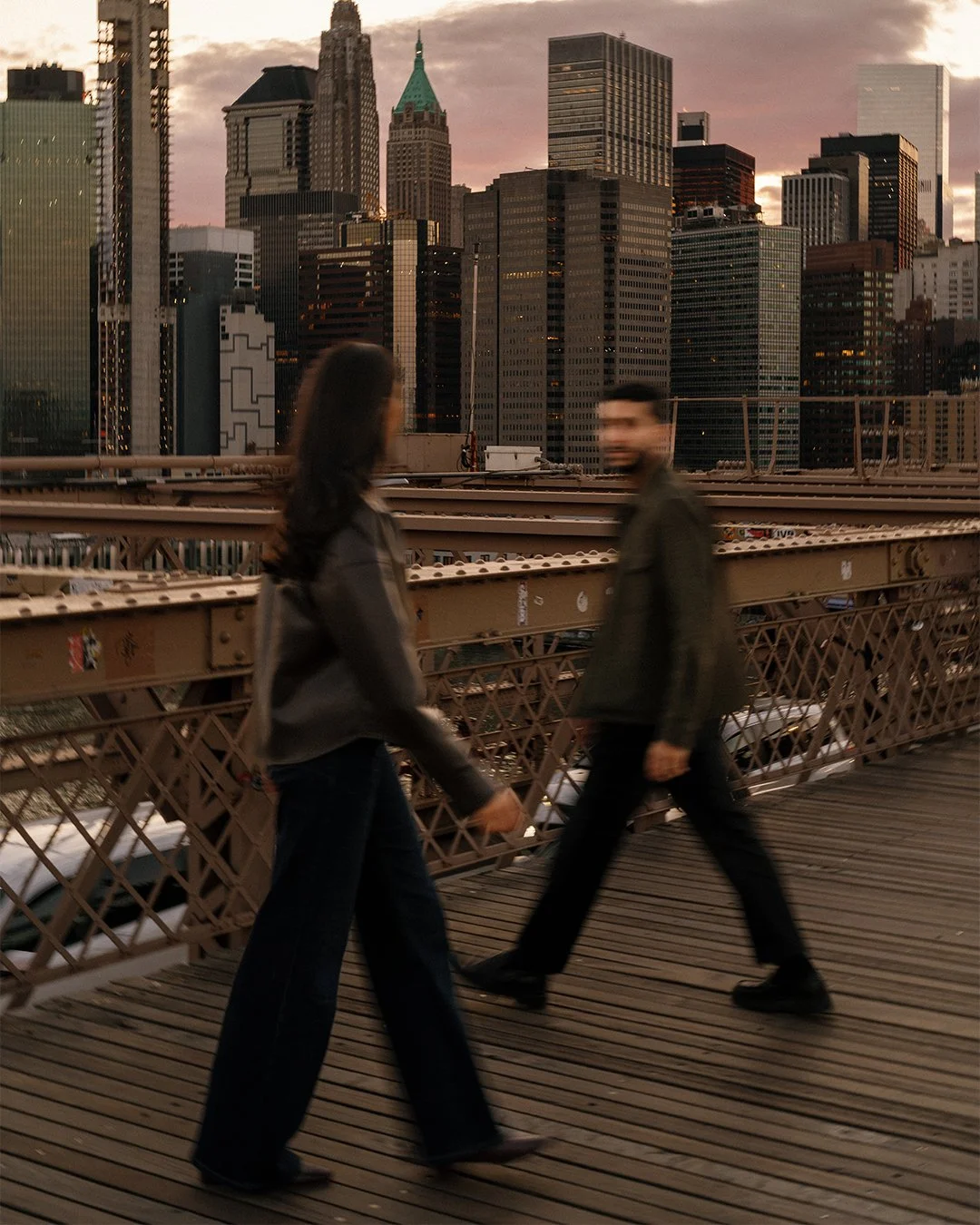 Couple motion blur on Brooklyn Bridge in front of NYC skyline during sunset
