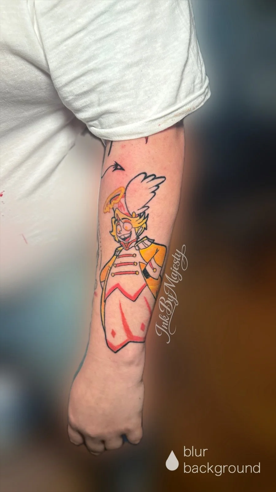 Colorful tattoo of a cartoon character, possibly a princess or royal figure, on the person's forearm. The character has blonde hair, wears a crown and a yellow and red outfit, and is smiling.