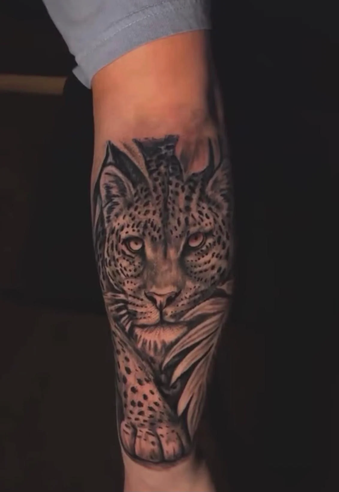 Tattoo of a leopard's face on a person's forearm