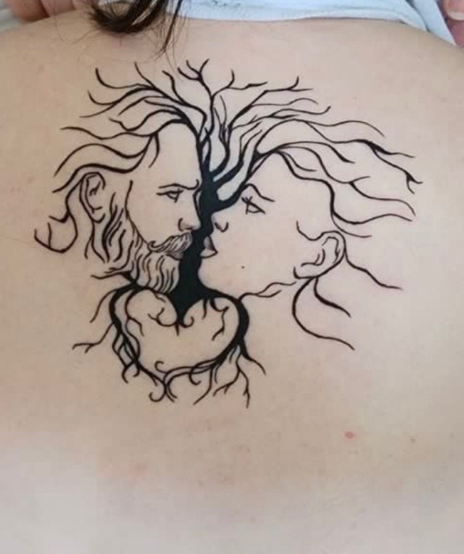 Tattoo of a tree forming the faces of a man with a beard and a woman, with their foreheads touching.