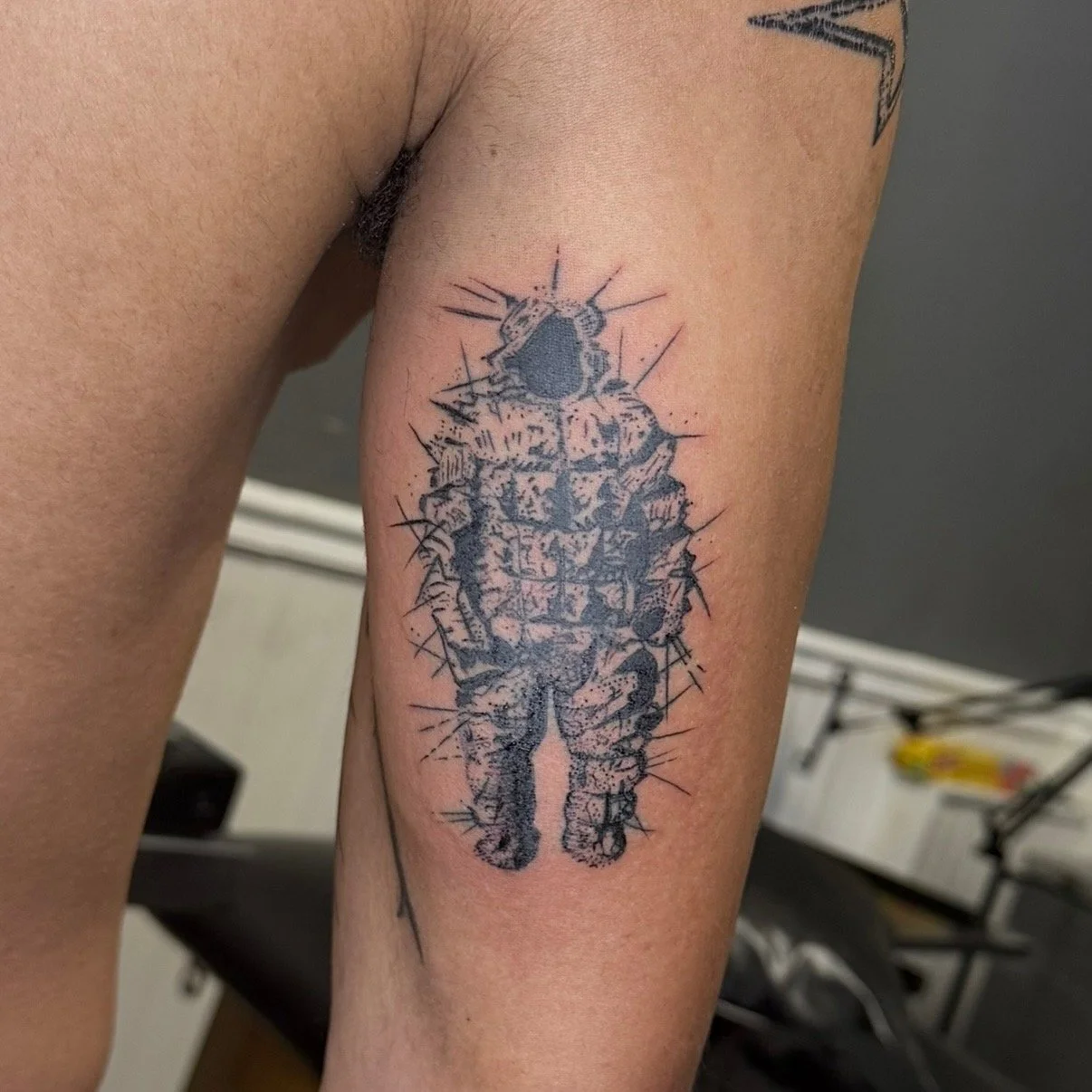A tattoo of a thorny cactus in blue ink on a person's upper arm.