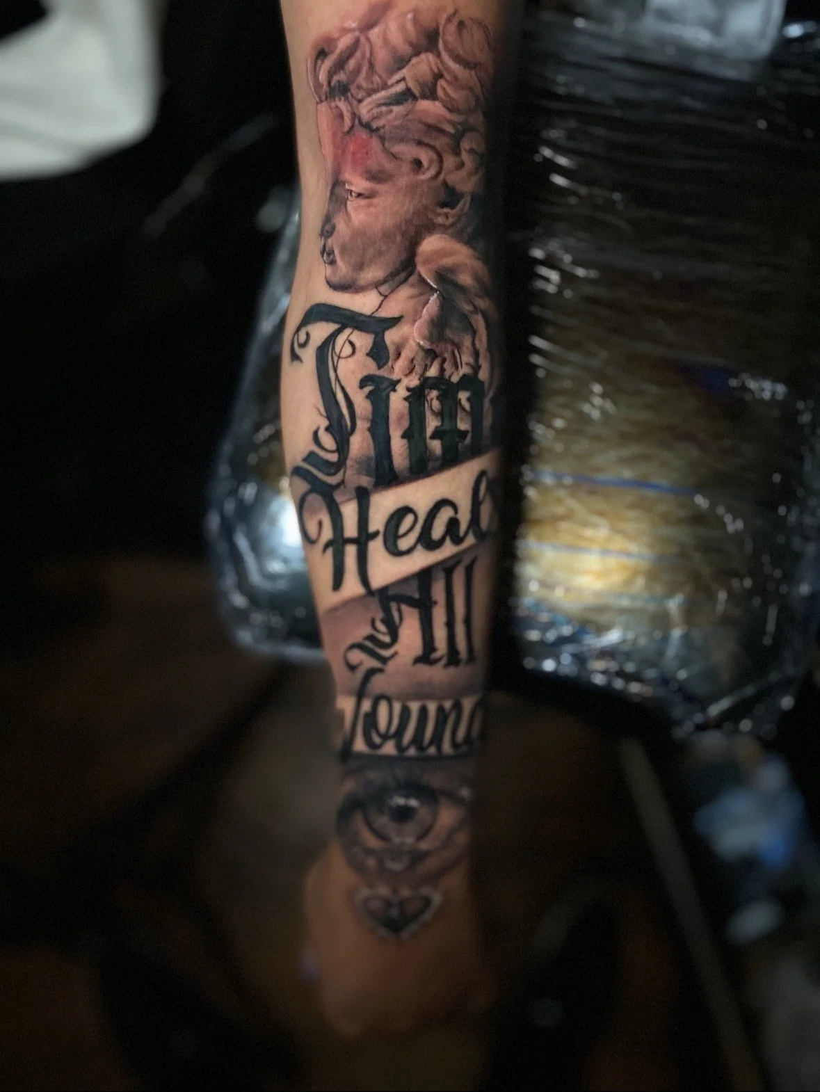 A person's arm with a tattoo of a dog's head, and words including "My Heart" and part of the word "Fours" in a decorative font.