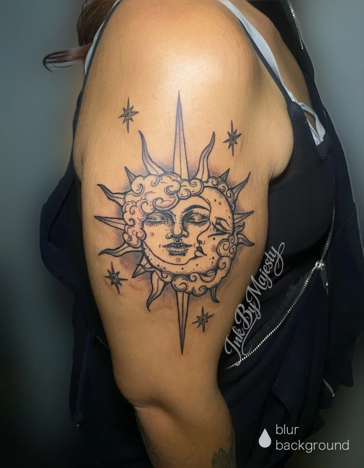Tattoo of a sun and moon with faces surrounded by stars on person's upper arm.